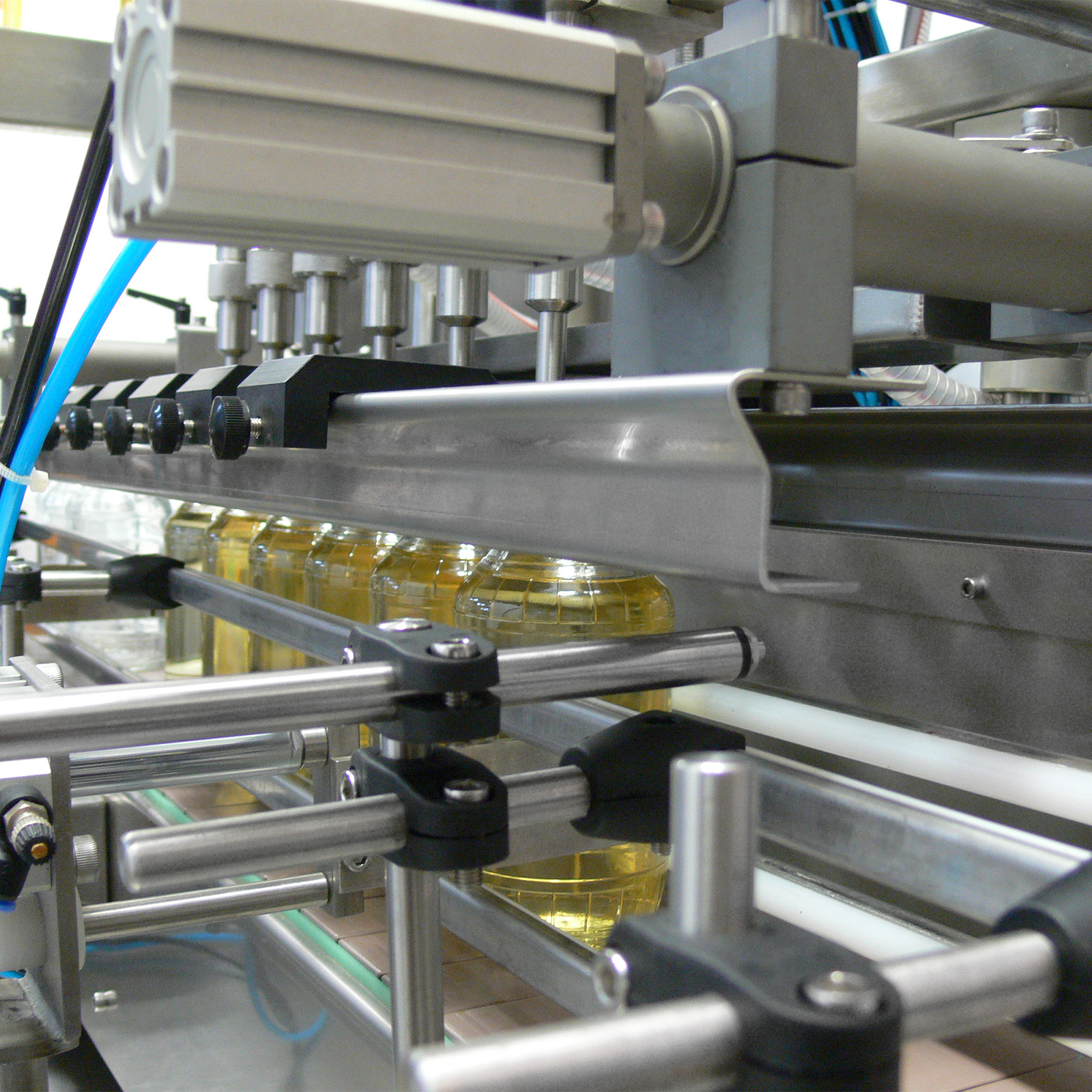 closeup of the 6 heads of the liquid filling machine dispensing liquid into 6 clear containers