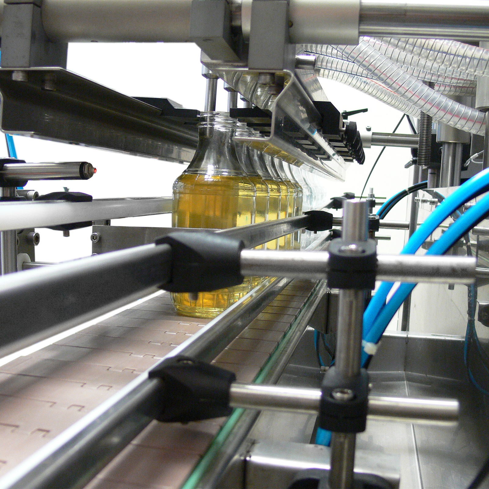 closeup of the 6 heads of the gravity liquid filling system dispensing liquid into 6 clear containers