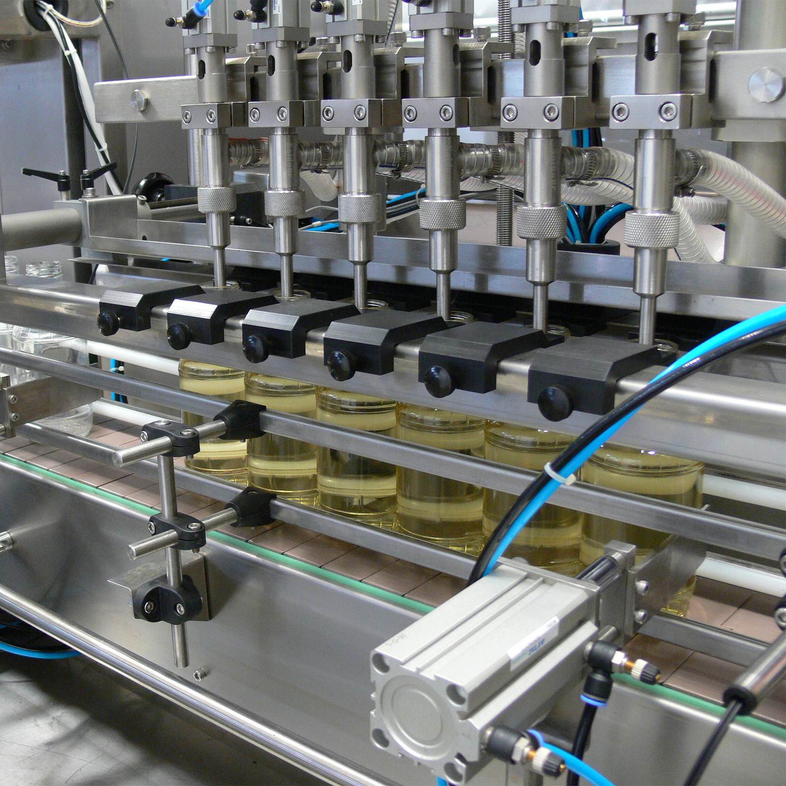 closeup of the 6 heads of the machine dispensing liquid into 6 clear containers