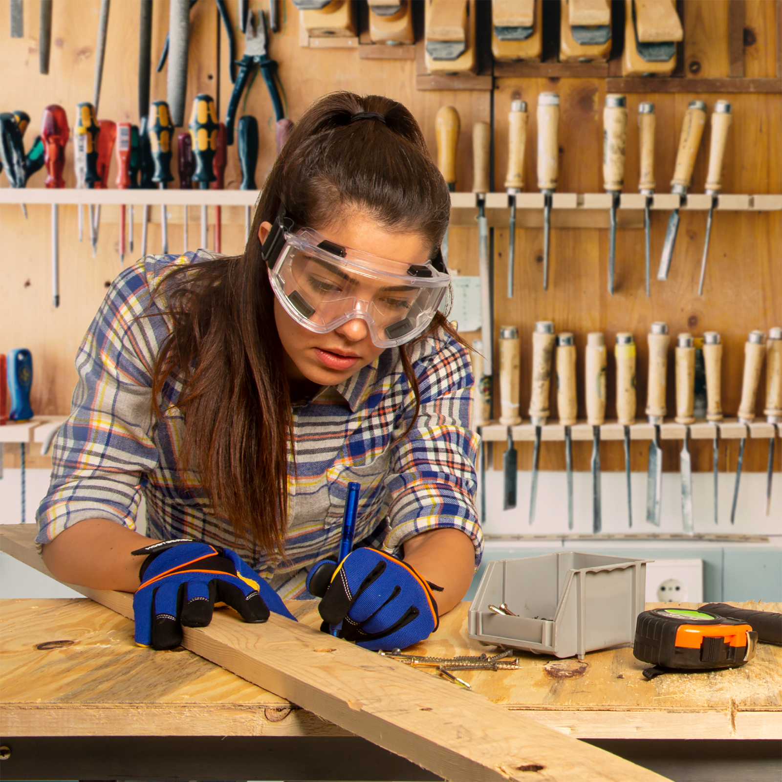 A woman wearing anti-fog ventilated safety goggles while working with wood and wood tools in her art studio