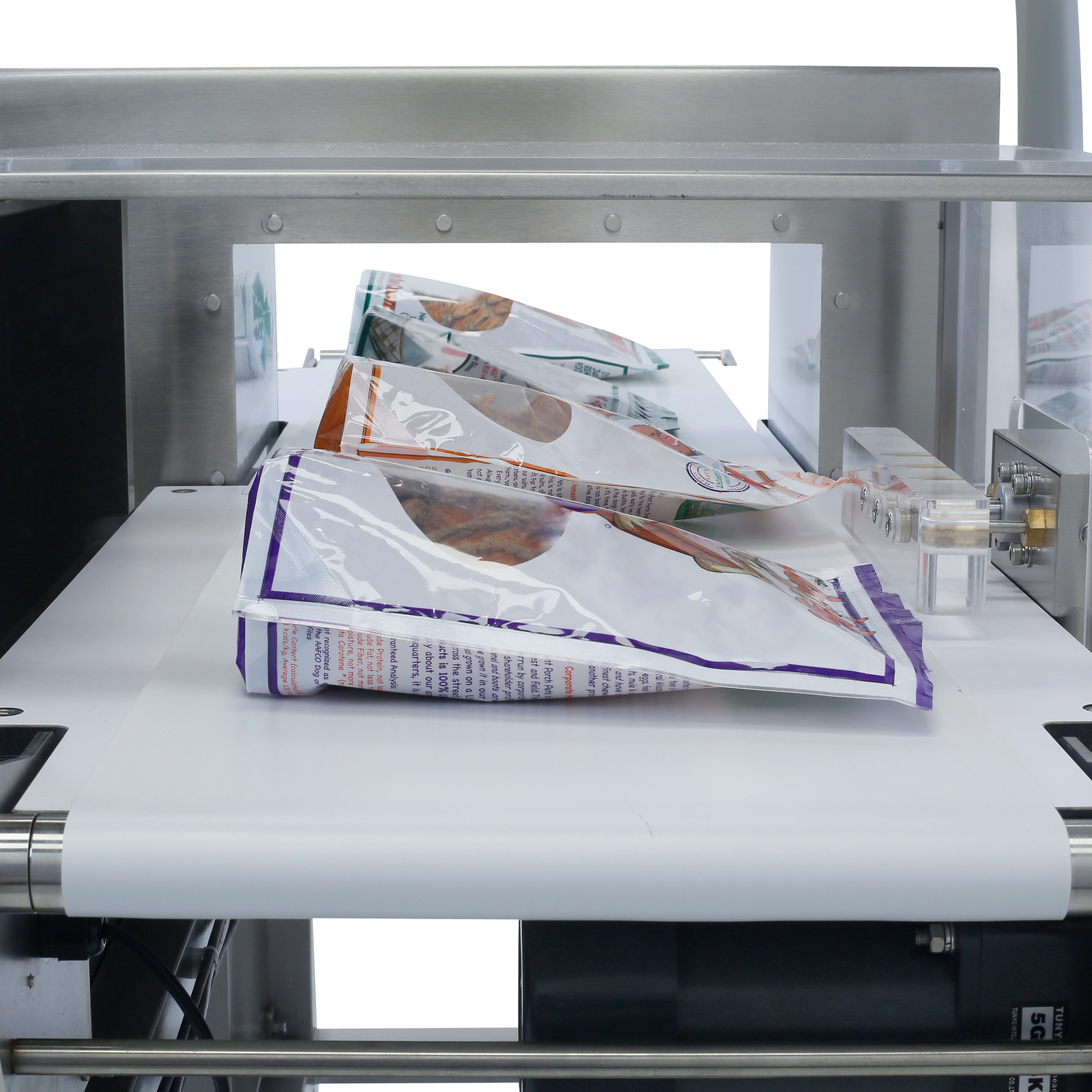 close-up of white sealed and filled bags of product passing through the JORES TECHNOLOGIES® stainless steel metal detector. Bags are positioned on top of the white conveyor,  the reject system is on the right side and the integrated disposal container is on the left.
