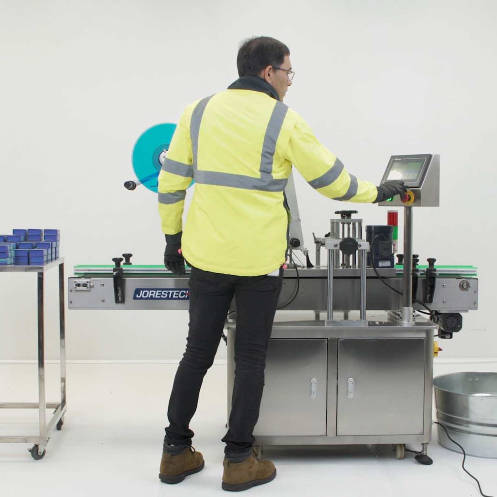 A person setting the digital control panel of the JORESTECH labeler for flat containers.