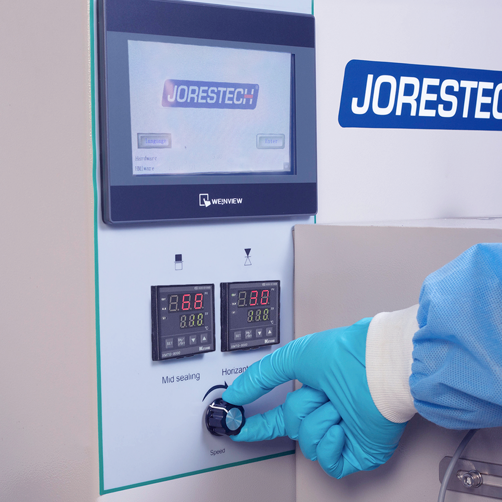 Operator wearing a blue PPE disposable glove is seen operating a Horizontal HFFS flow pack machine. The LCD screen display is shown, along with a few of the machine's control features