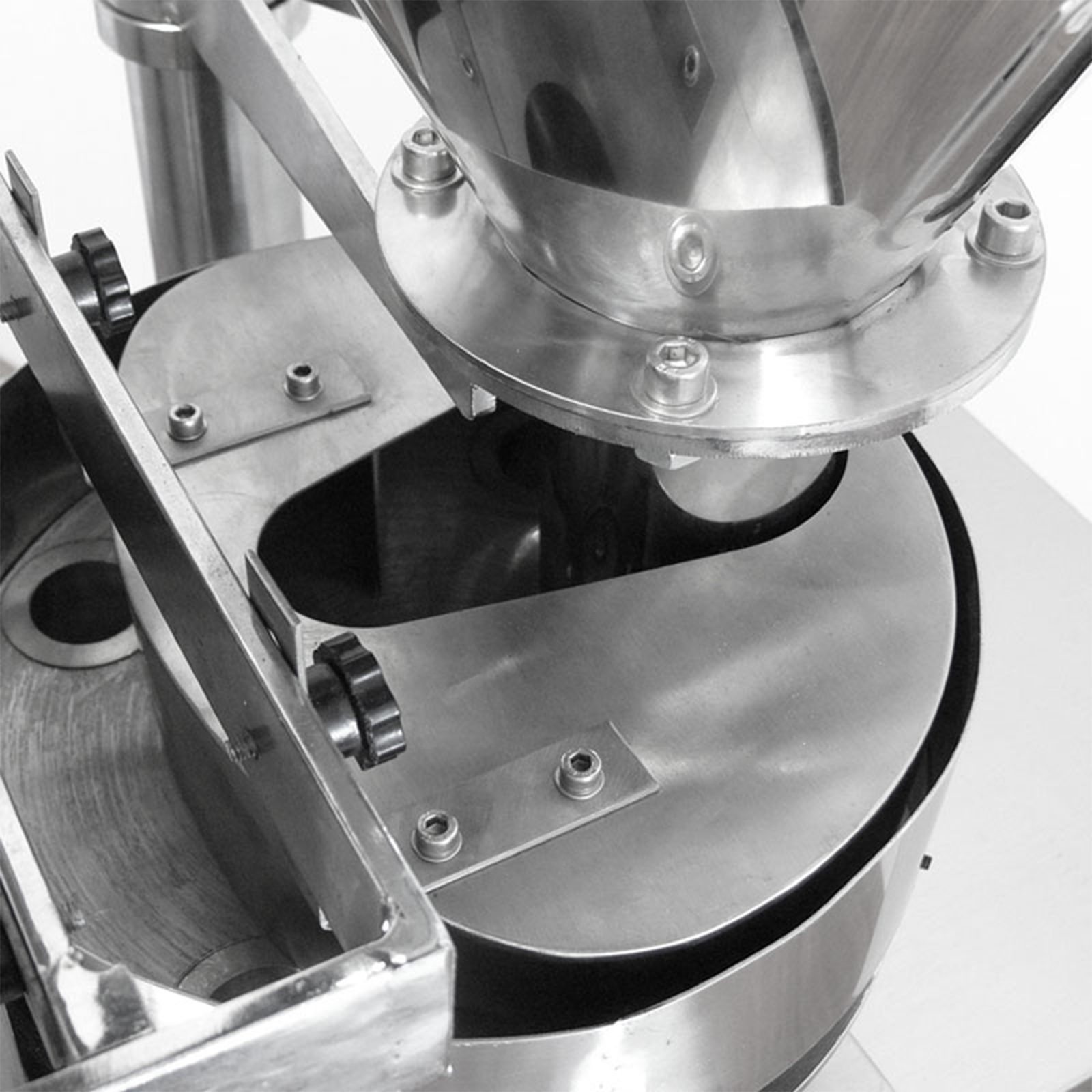 Part of a VFFS vertical form fill and seal packaging system, where the stainless steel feeding hopper can be appreciated along with the rotating disc and volumetric measuring cups. 