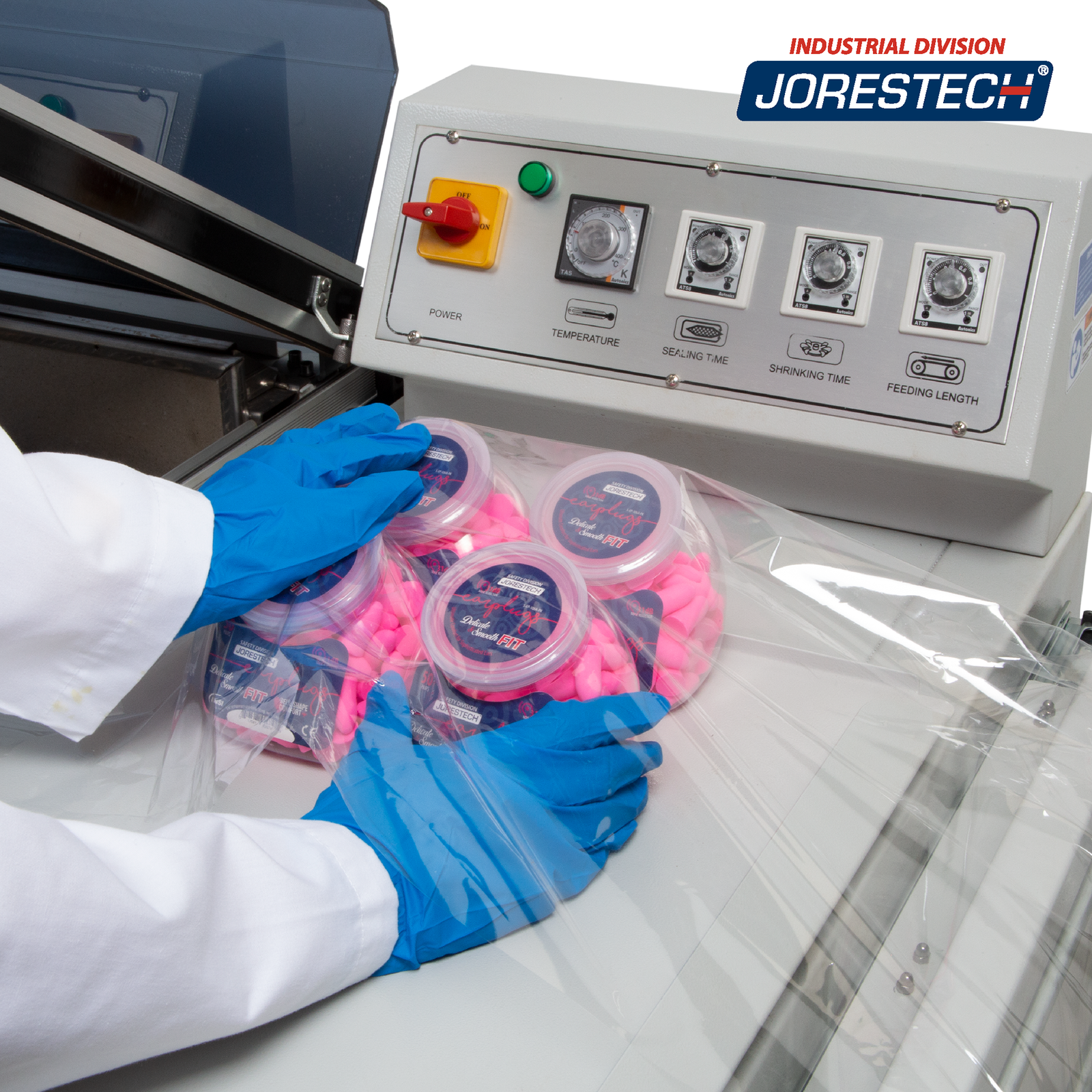 Close up of the shrink chamber or a JORES TECHNOLOGIES®  shrink wrapping system and a person locating 4 medium size containers inside a centerfold polyolefin material before entering the heat shrink chamber to make a bundle.