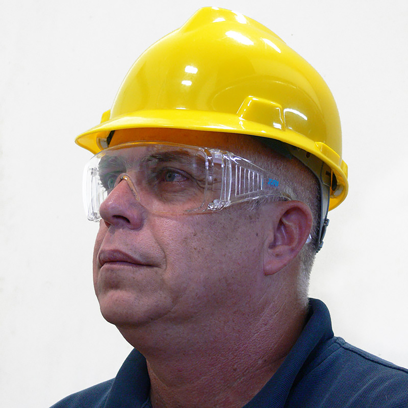 A man wearing a hard hat and the clear safety overglasses for high impact protection
