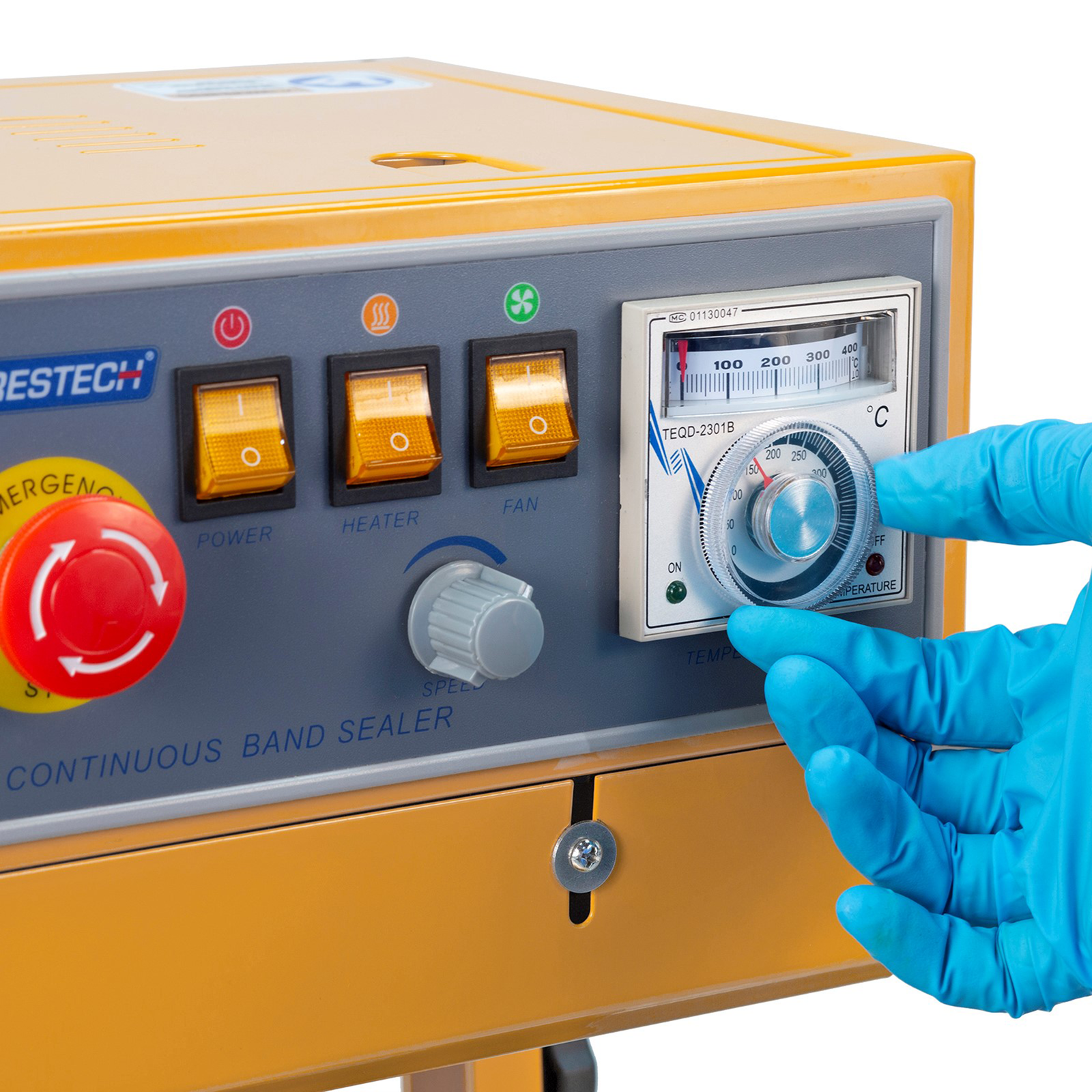 operator wearing blue gloves adjusting temperature on the analog dial on control panel of the Jorestech continuous band sealer 