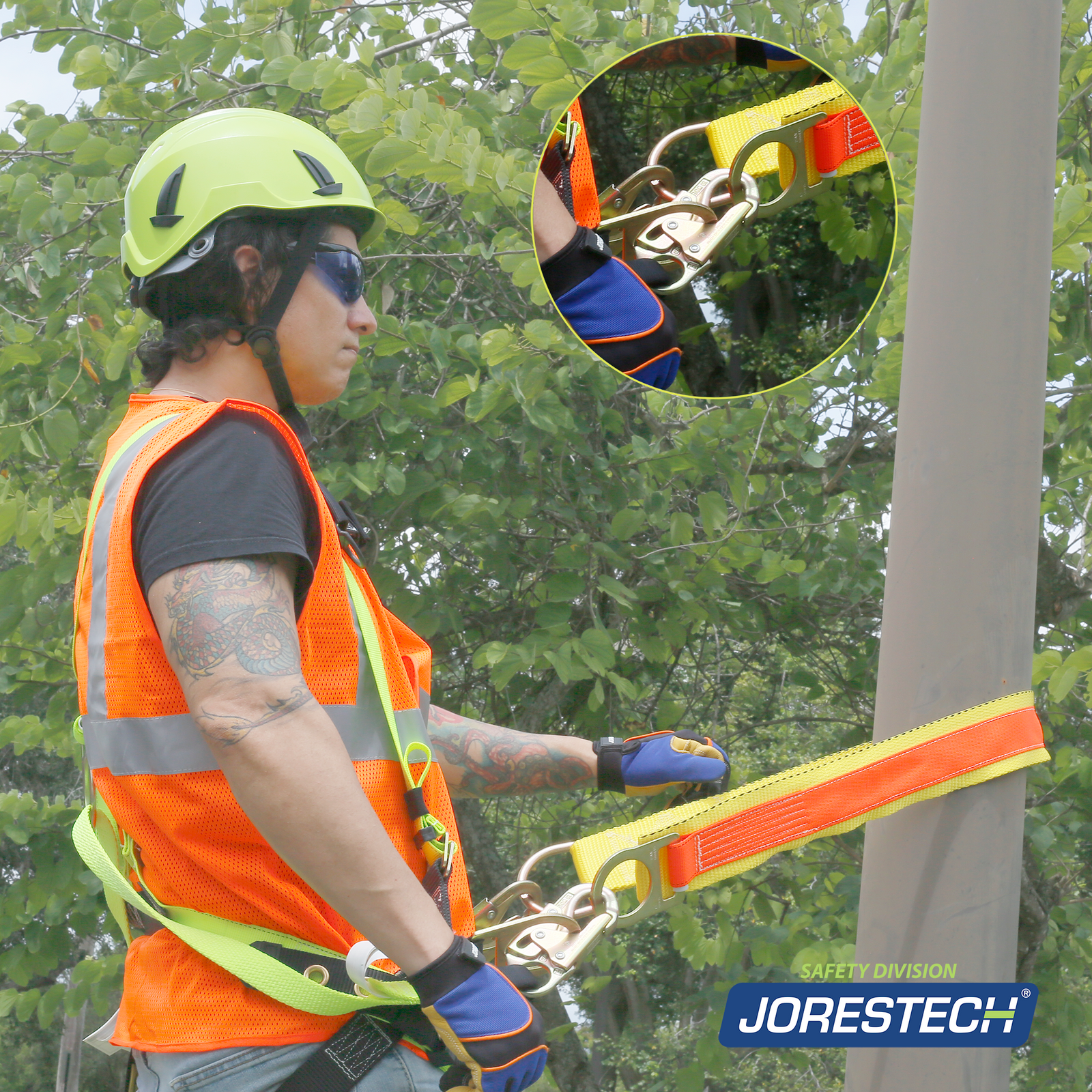 A worker using the JORESTECH cross arm anchor strap with double ring to hold himself to a round structure. The man is wearing a hard hat, vi visibility clothing and the cross armor strap is hooked to his 3 D ring harness.