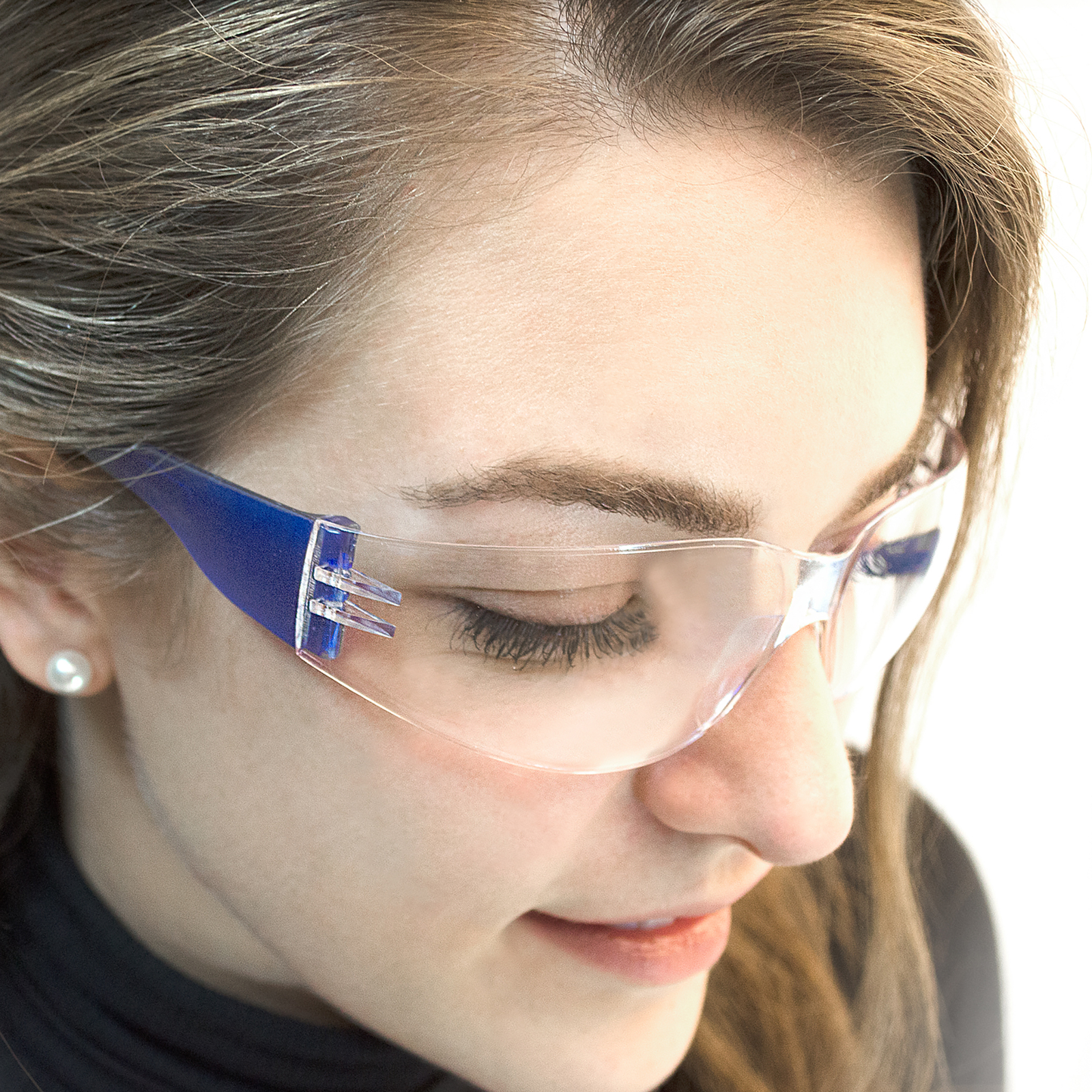 A woman wearing the clear and blue JORESTECH ANSI compliant safety glasses for high impact