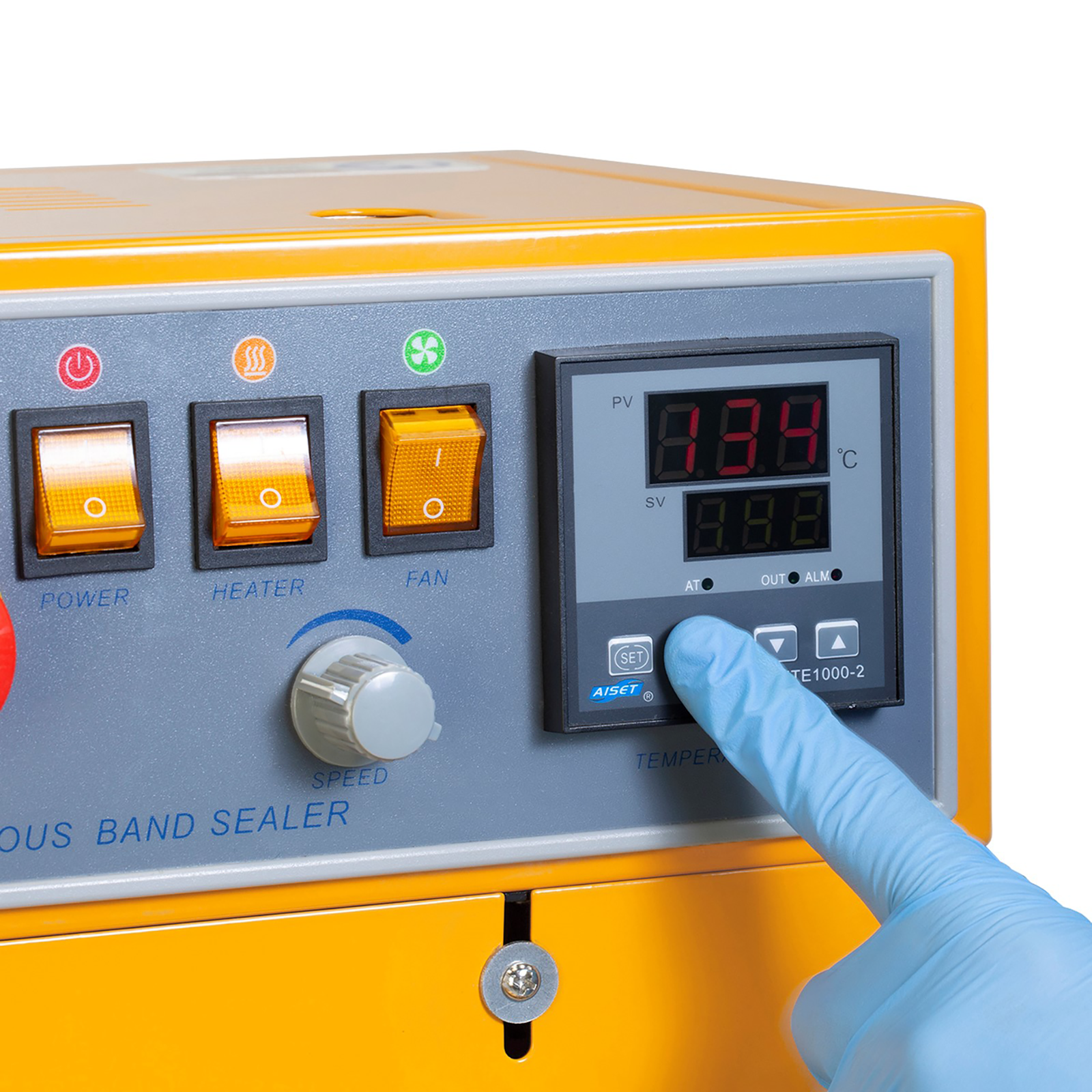 operator wearing blue gloves adjusting temperature on the analog dial on control panel of the Jorestech continuous band sealer