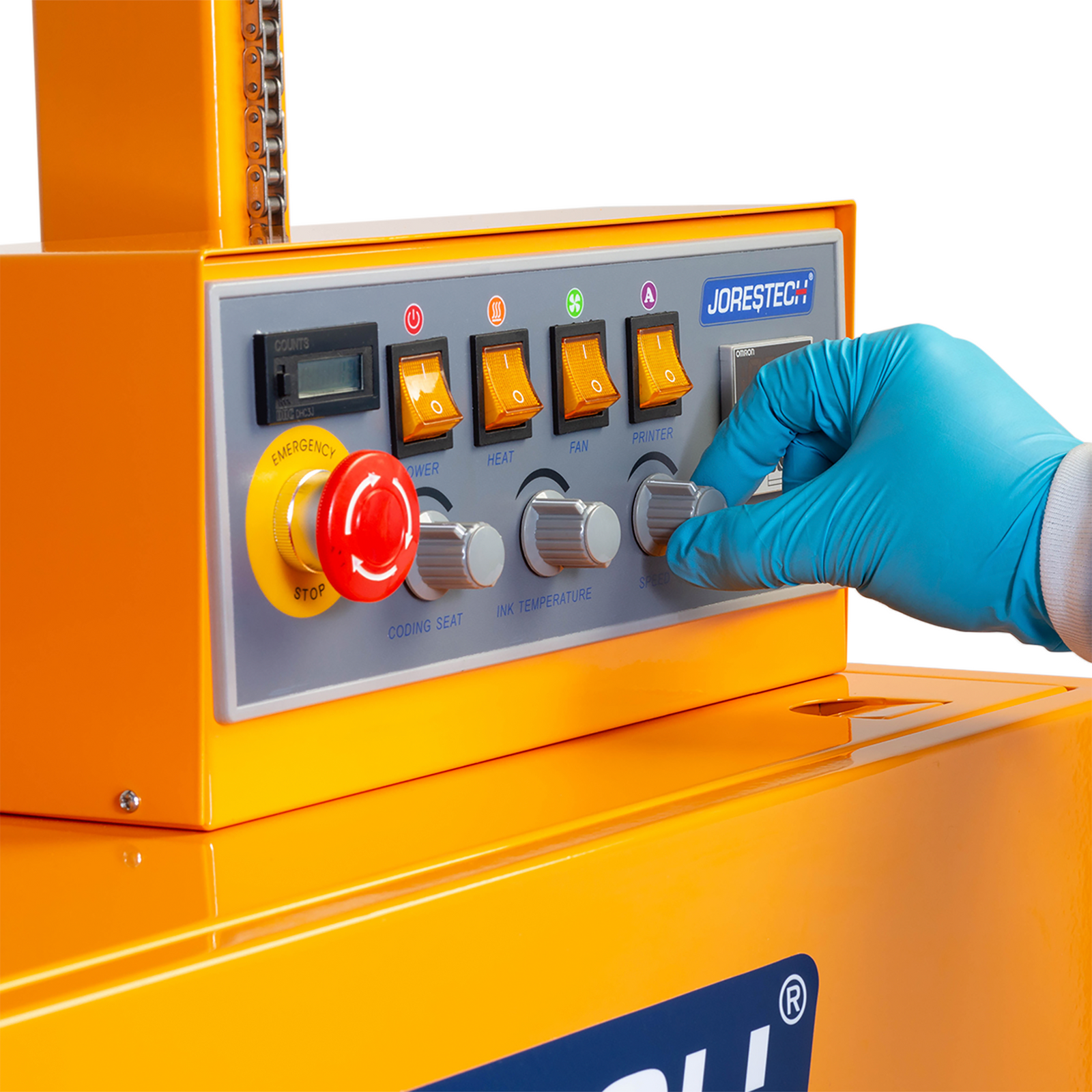 operator wearing blue disposable gloves adjusting speed dial on a grey button on the control panel of the JORESTECH vertical continuous band sealer for large bags with coder.