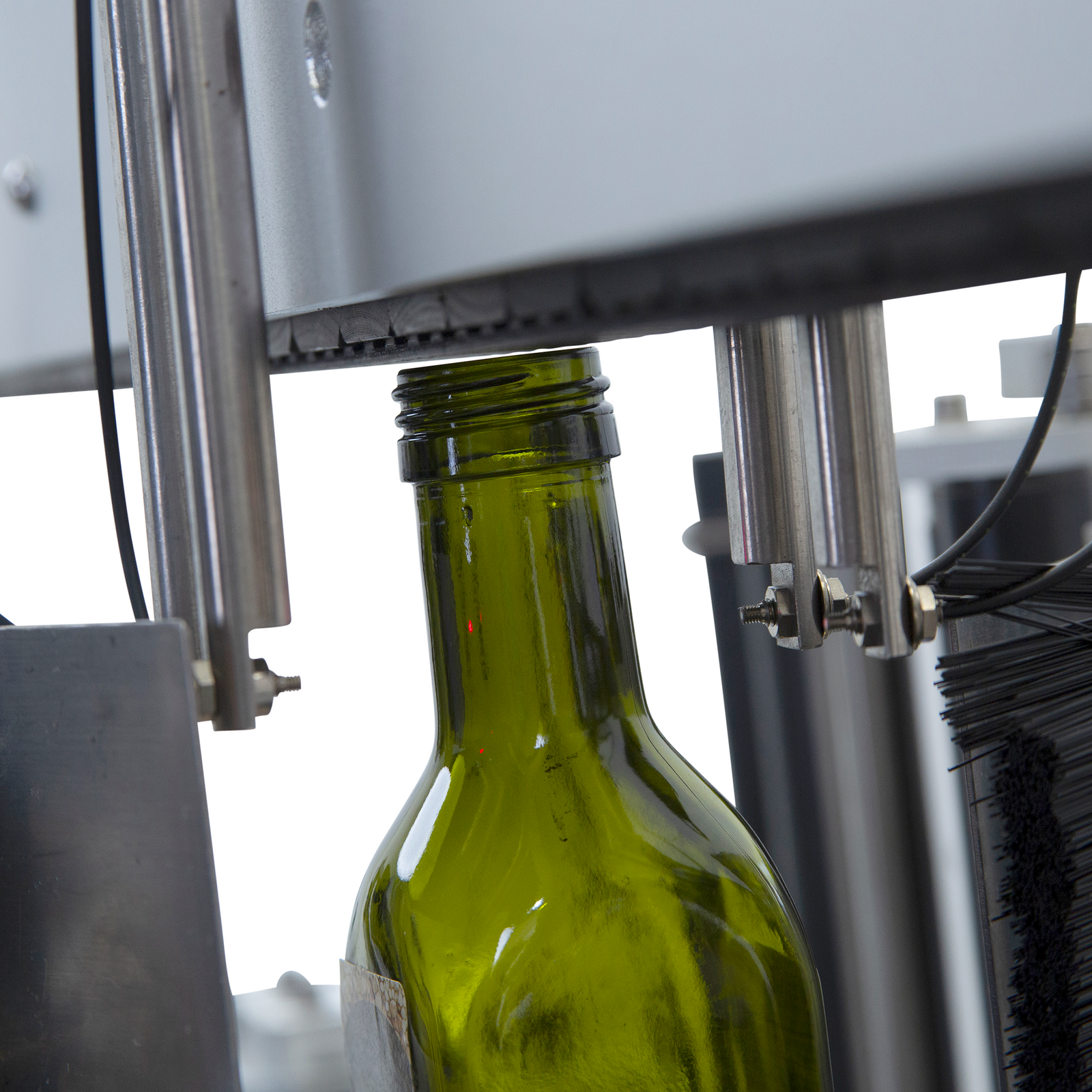close up of a green glass bottle inside of the JORESTECH dual automatic label applicator