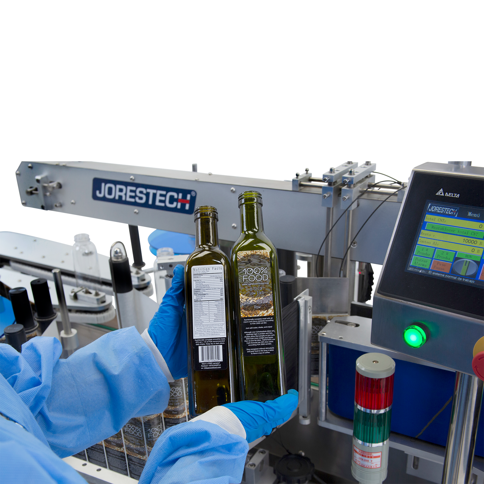man wearing blue gloves holding two green oil bottles with labels placed on them after using the JORESTECH dual automatic label applicator for flat and round containers shown in the back