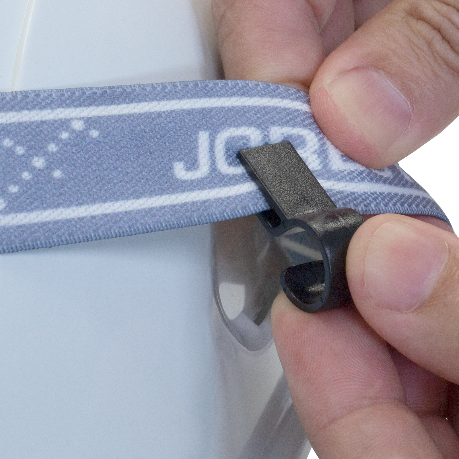 Close up of a person inserting the elastic strap of a headlamp into the Jorestech hard hat headlamp clip which will be in a hard hat