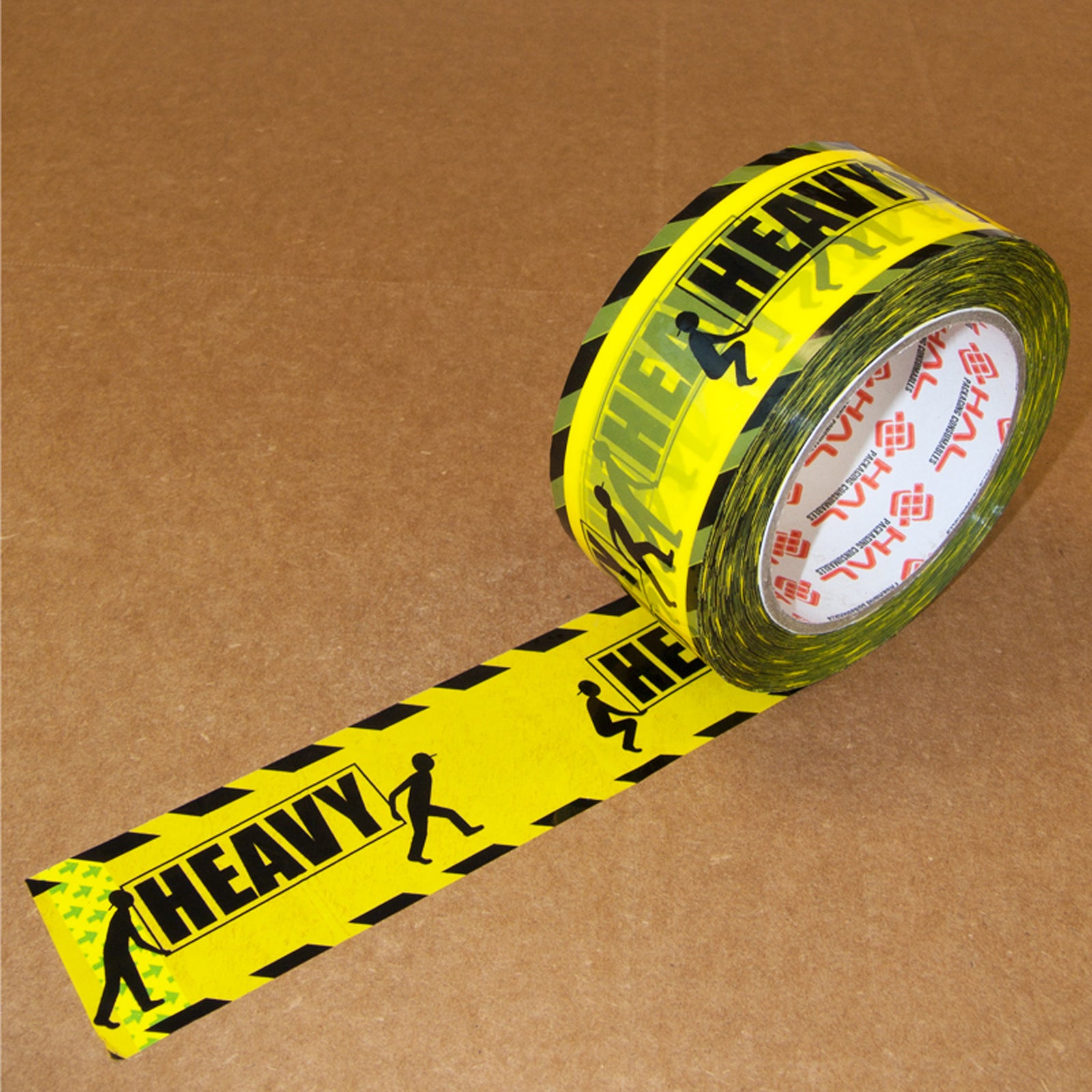 yellow and black printed packaging tape with two men figures holding a sign that says heavy on the tape on top of brown box