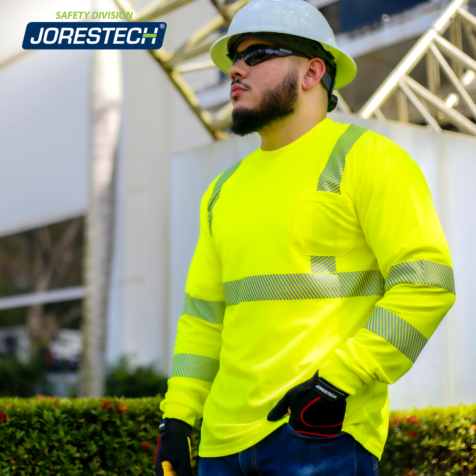 A worker standing close to a metal structure while wearing the JORESTECH yellow high visibility heat transfer reflective safety long sleeve shirt, a white hard hat and black working gloves