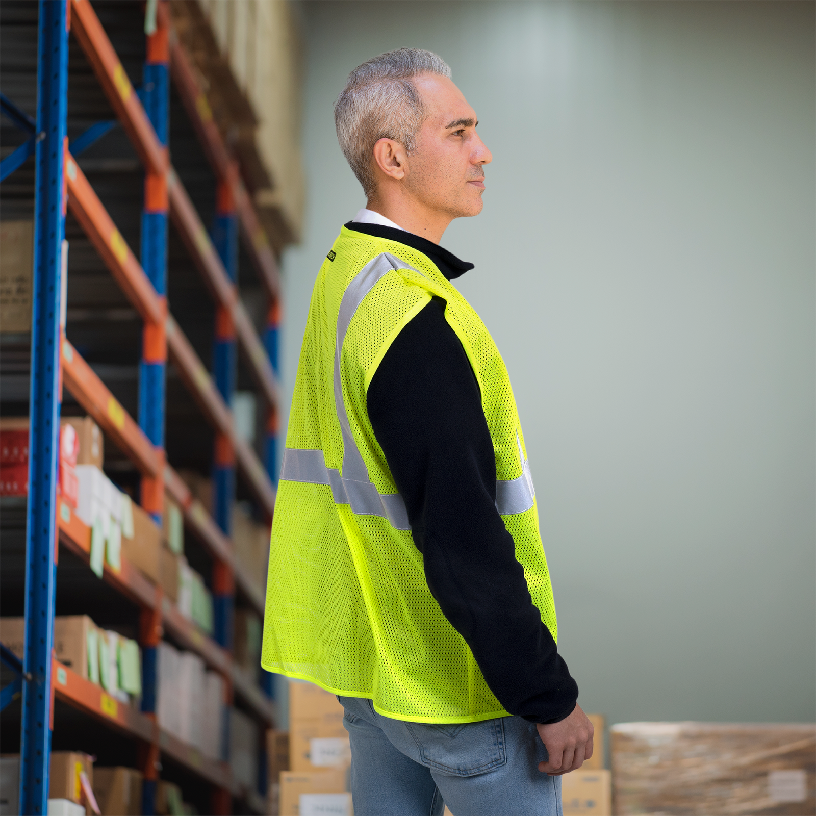 Worker wearing the lime hi vis safety vest for protection while he is working in a warehouse