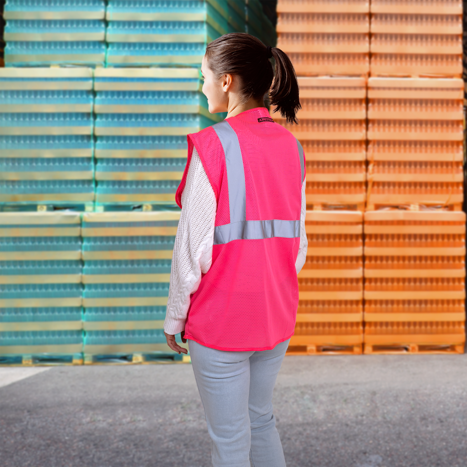 Back of a woman wearing the JORESTECH pink safety vest with 2 inches reflective strips and one pocket