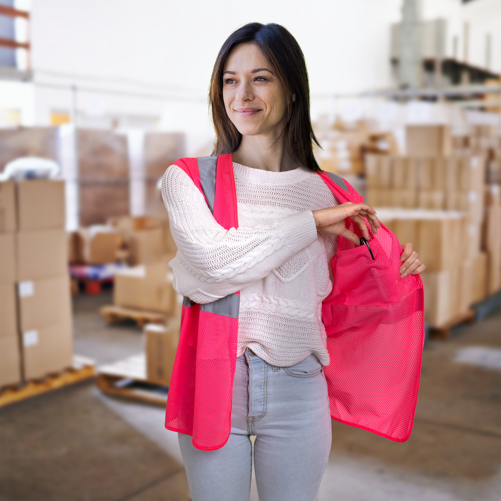 Woman wearing a High visibility pink safety vest inside a space filled with boxes