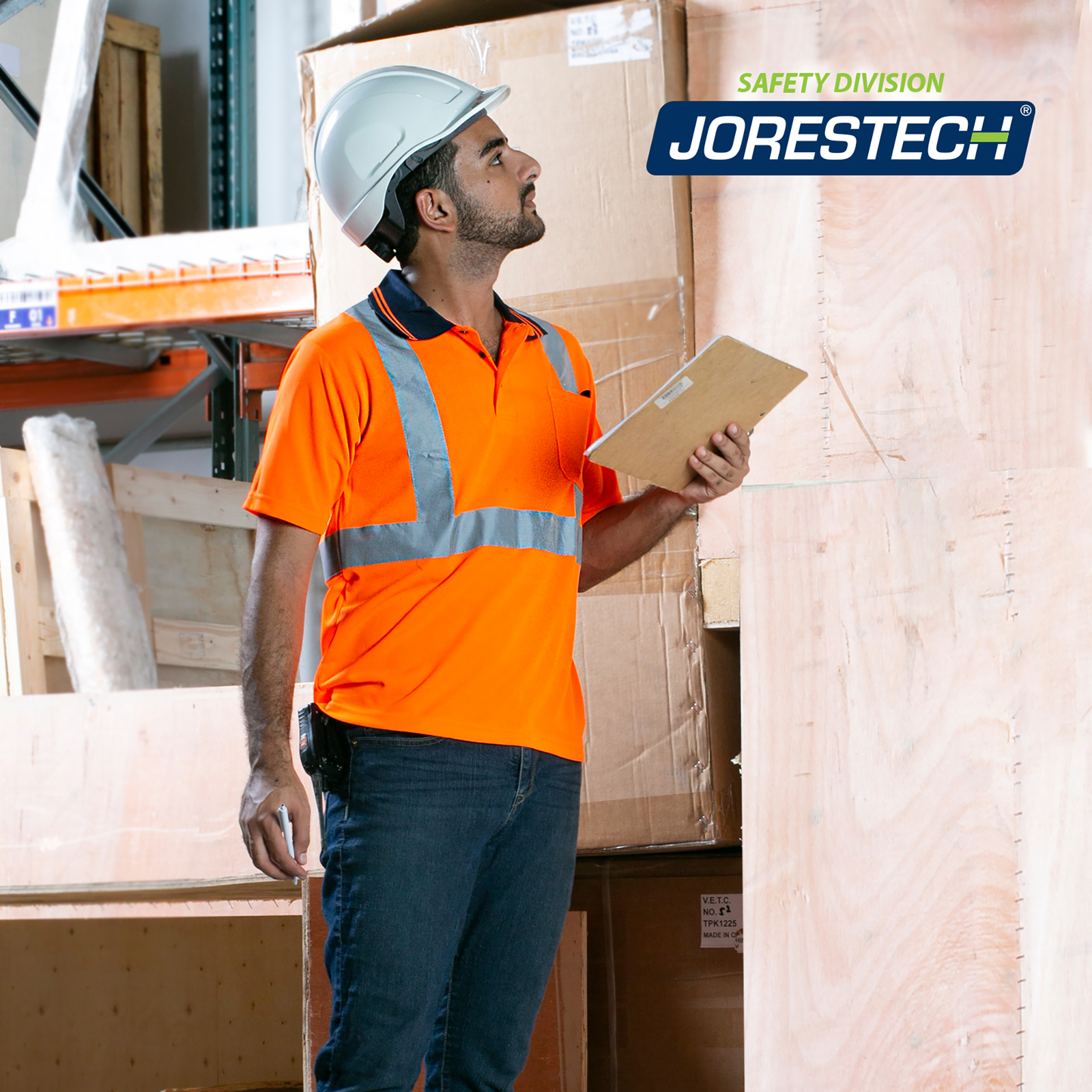 Worker  wearing an orange JORESTECH safety polo shirt while doing inventory inside a warehouse.
