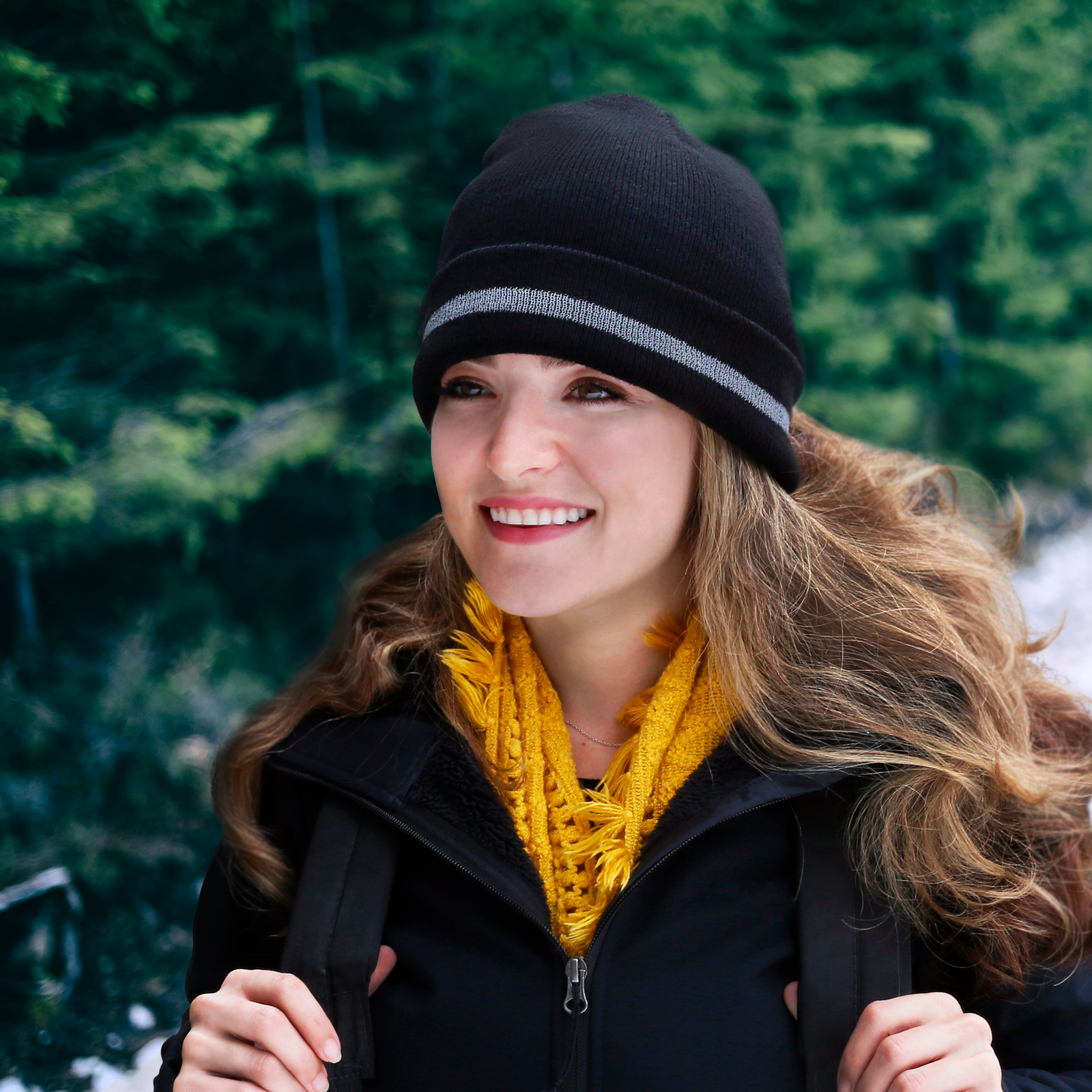 A woman wearing the back JORESTECH beanie with reflective stripe while outdoors doing exercise
