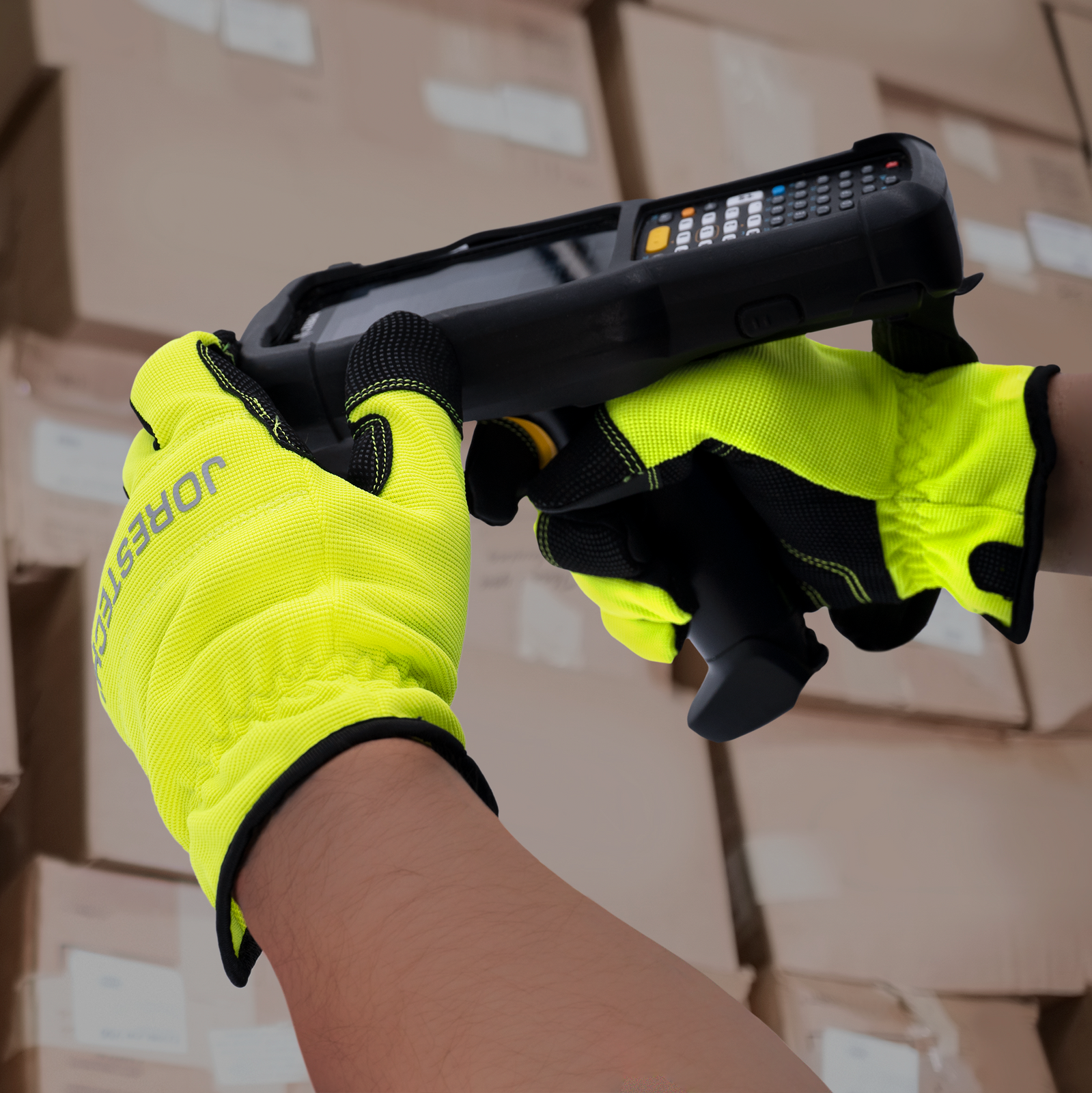 A worker operating a bar code finder in a warehouse while wearing the touchscreen safety work gloves
