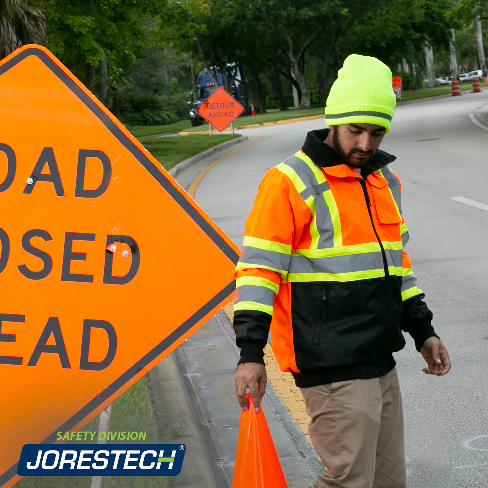 Worker wearing the orange JORESTECH Hi-vis two tone safety bomber jacket with reflective stripes and a reflective X for road construction.
