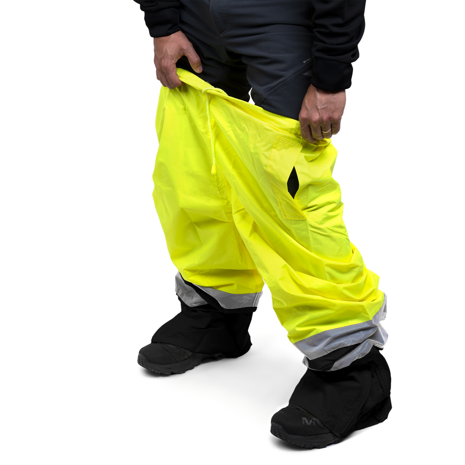 A person putting on the JORESTECH yellow and black safety rain pants with reflective strips