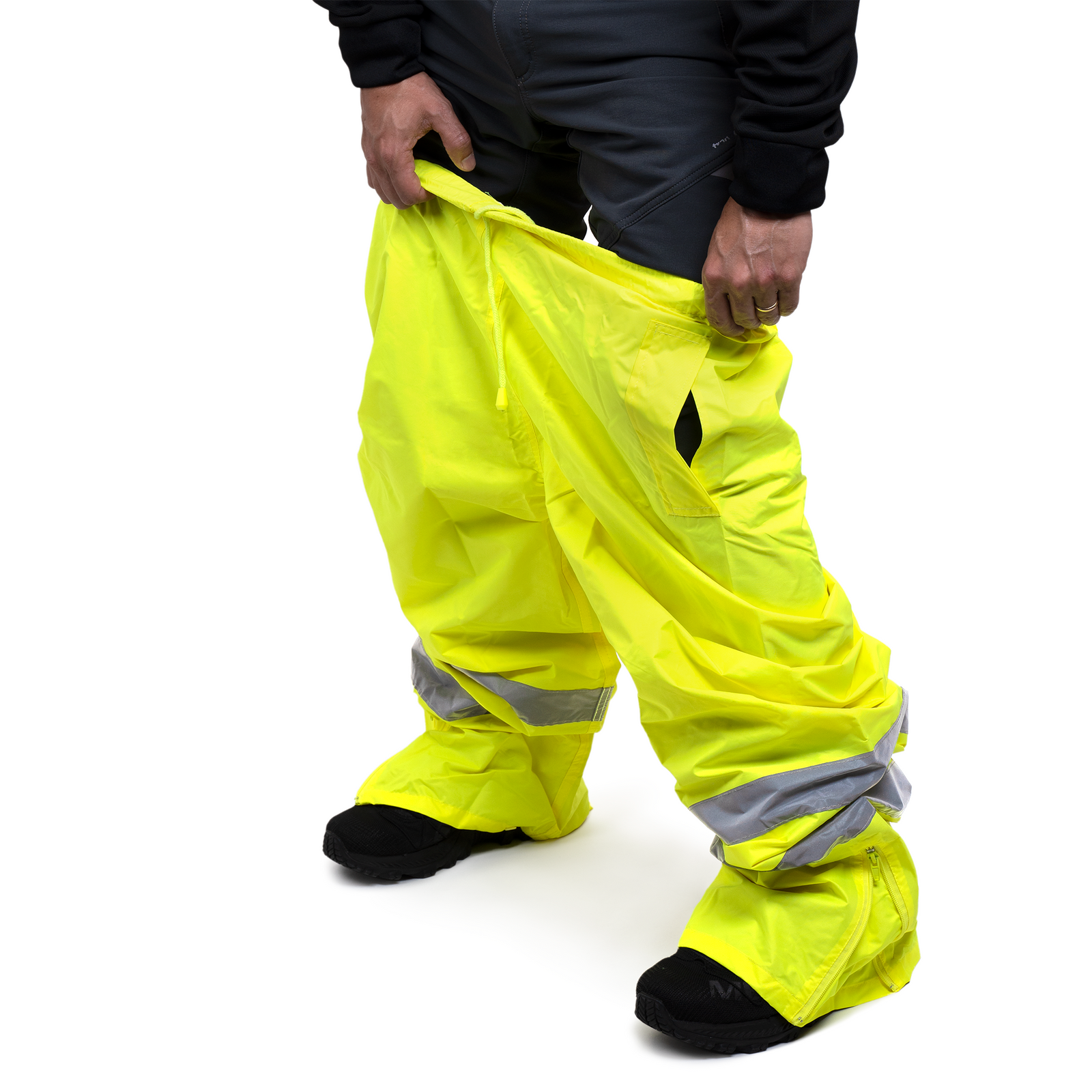A person putting on the JORESTECH hi vis yellow safety rain pants with reflective strips