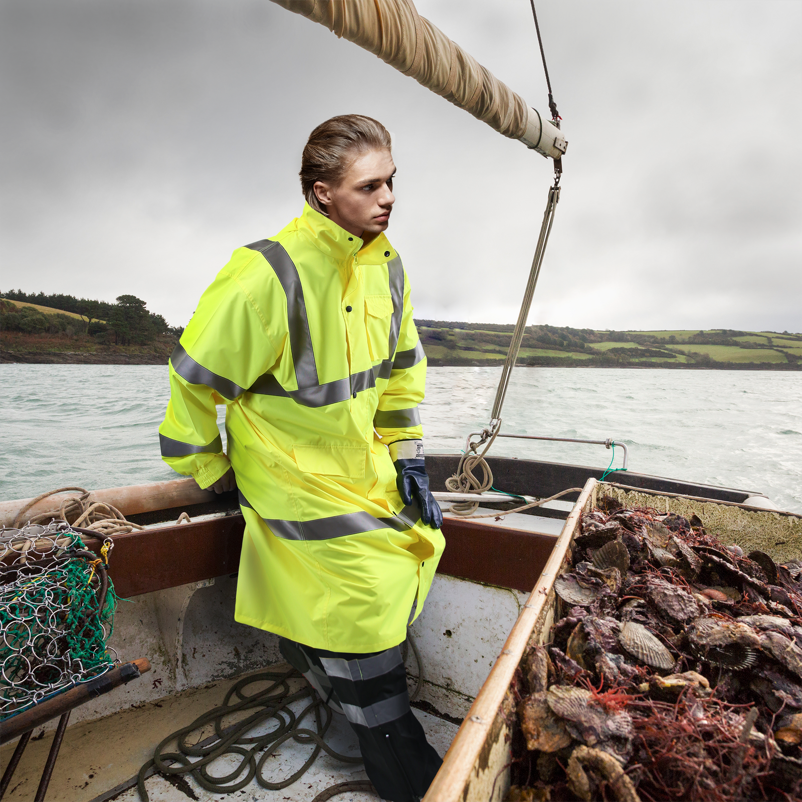 A fisherman standing on a boat while catching crabs wearing the Hi vis JORESTECH waterproof rain jacket in a cloudy day.