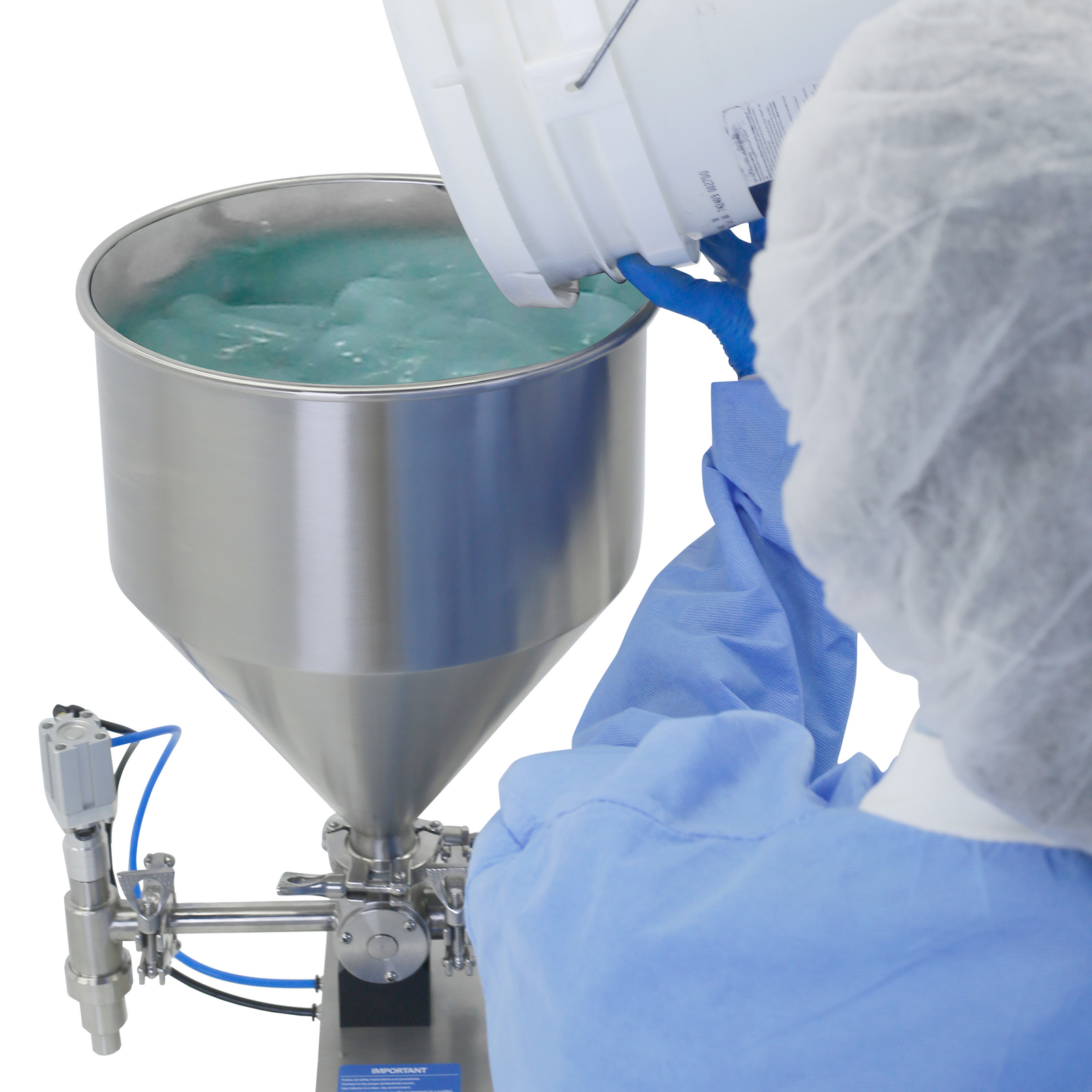 Close up of a person wearing disposable clothing and gloves standing beside a Piston filler. He is dispensing a green gel into the hopper of a table top JORESTECH Piston filler for paste