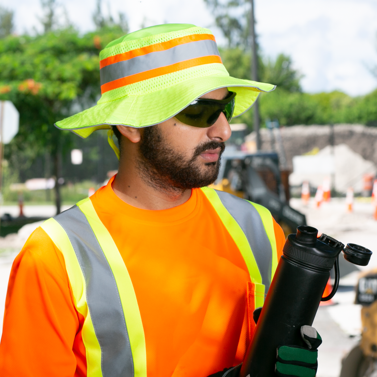 A man wearing a lime JORESTECH boonie hat, matching shirt,  while working in a construction under the sun