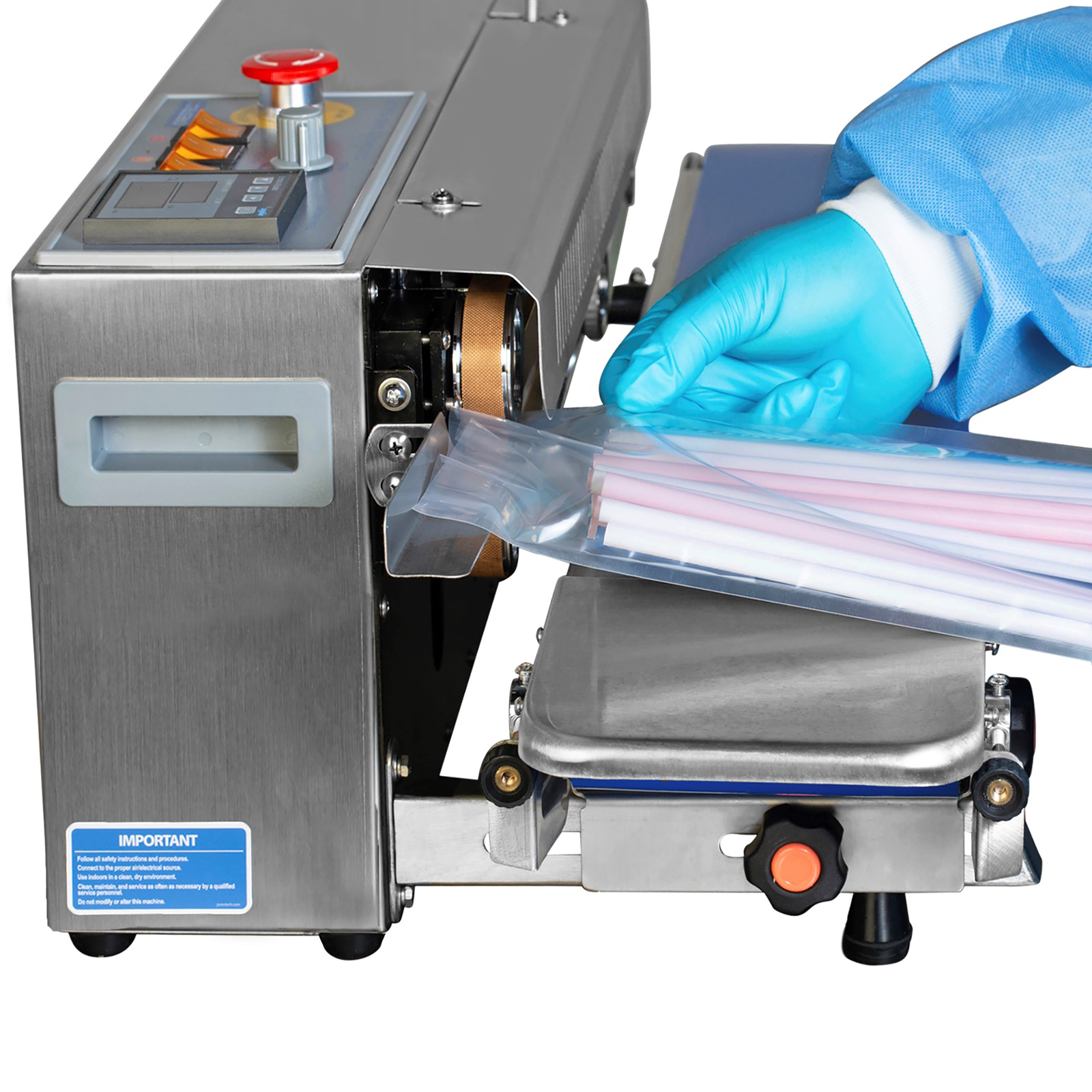 Operator wearing blue disposable gloves is inserting a clear bag filled with multi-colored straws from left side of a JORESTECH left to right continuous band sealer with digital temperature control panel to get the plastic bag sealed.