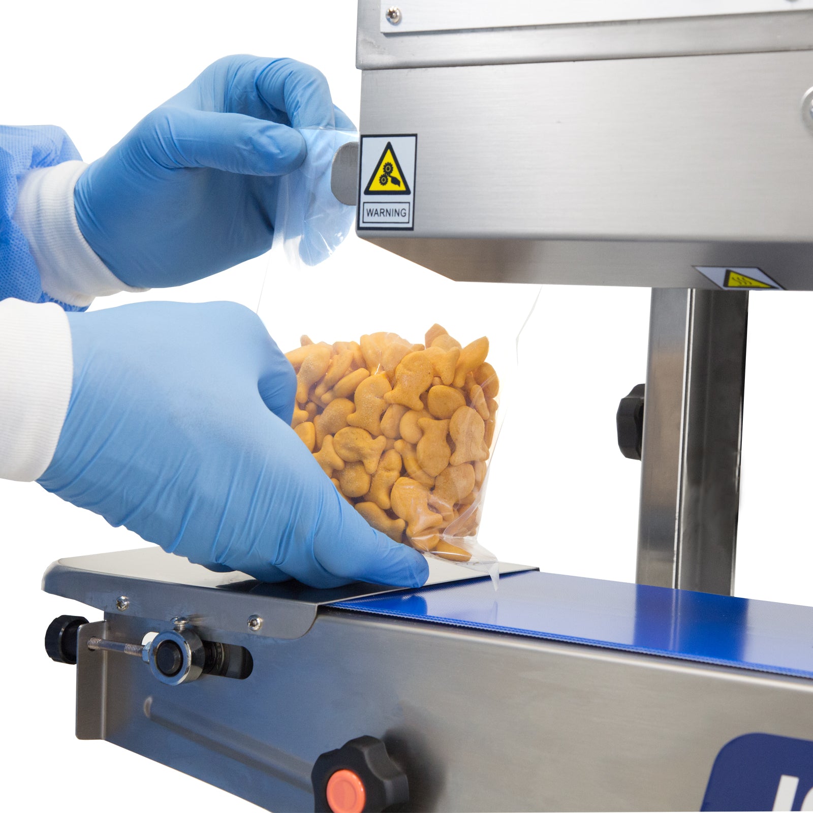 operator wearing blue gloves inserting plastic bag with orange fish-shaped crackers