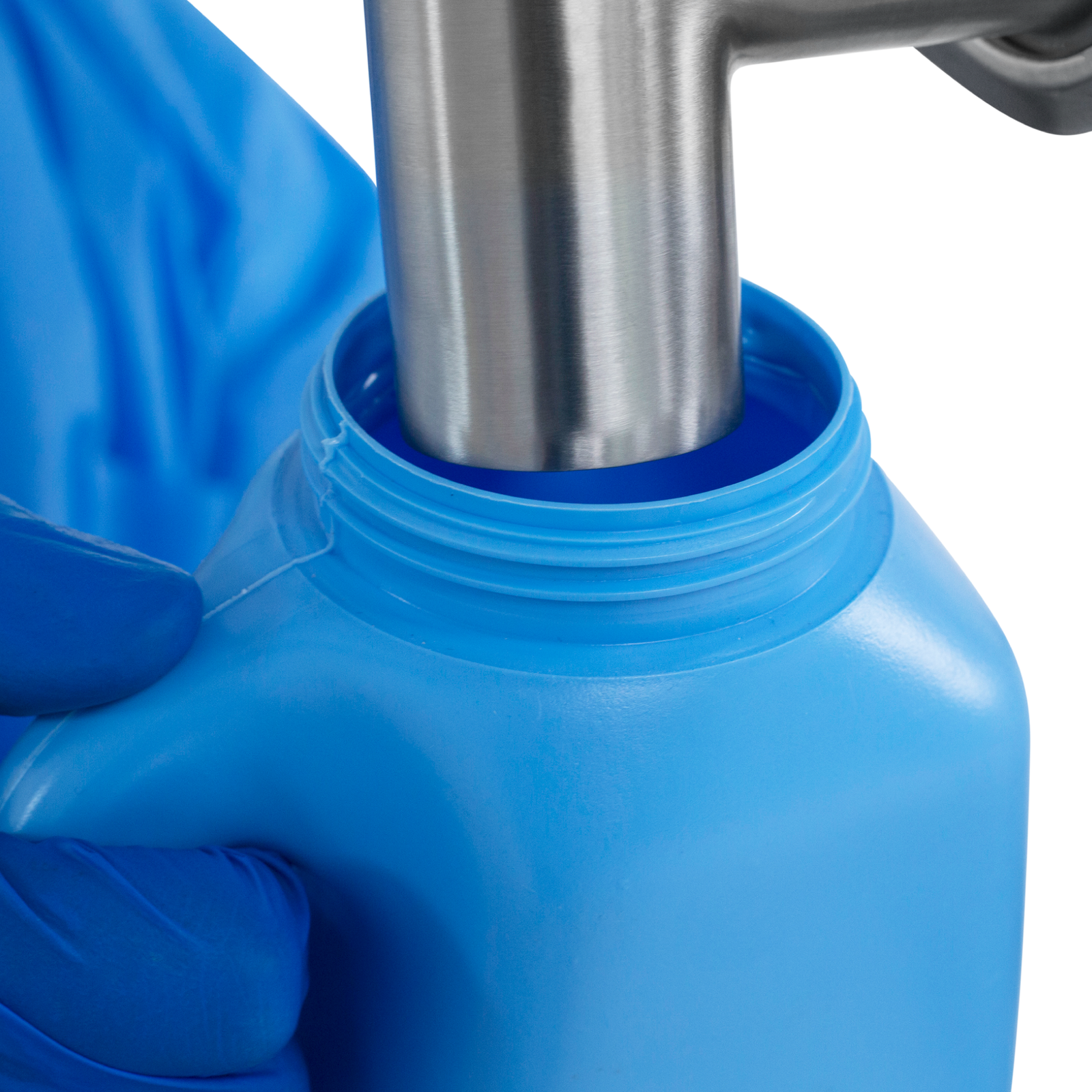 A worker wearing nitrile safety gloves operating the Jorestech Low Viscosity Piston Filler. The person is positioning a 5000ml bottle below the tip of the non-drip nozzle to be filled with accuracy by the liquid filling machine.