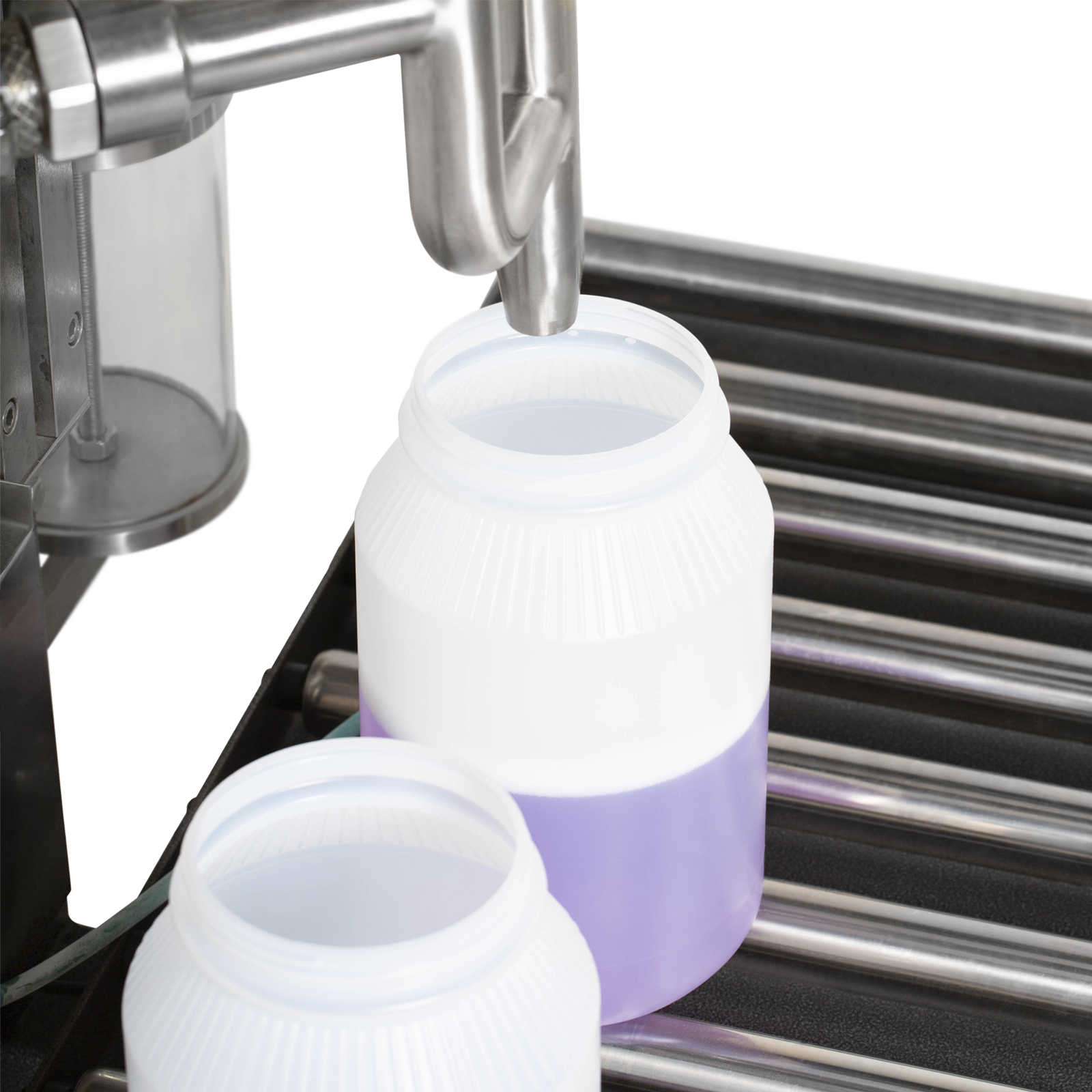 Closeup of two extra large containers positioned on top of the roller conveyors. One of them is being filled with a purple solution by the net weight liquid filler