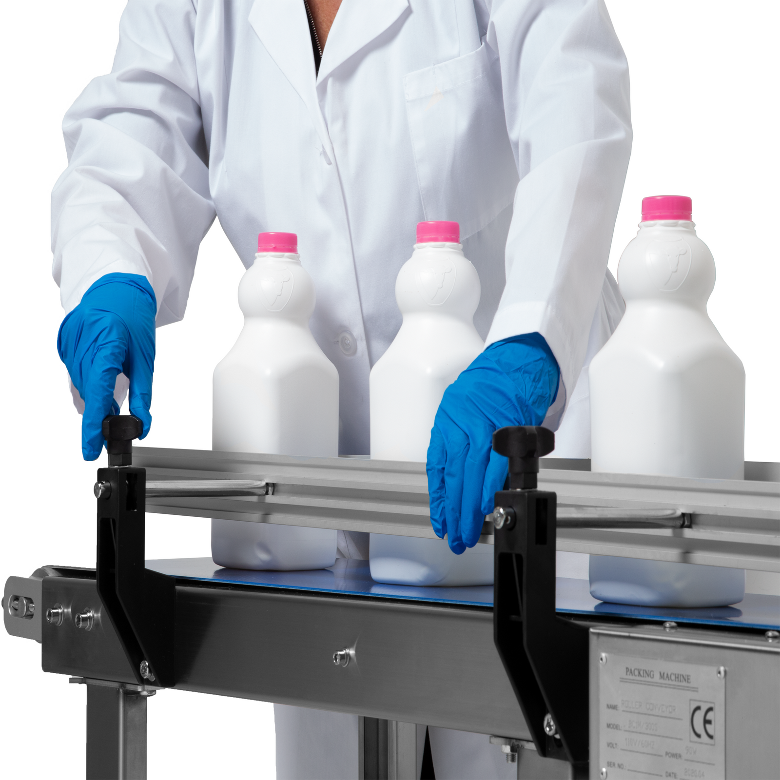 operator wearing white lab coat and blue gloves adjusting side rail on conveyor belt with white milk bottles
