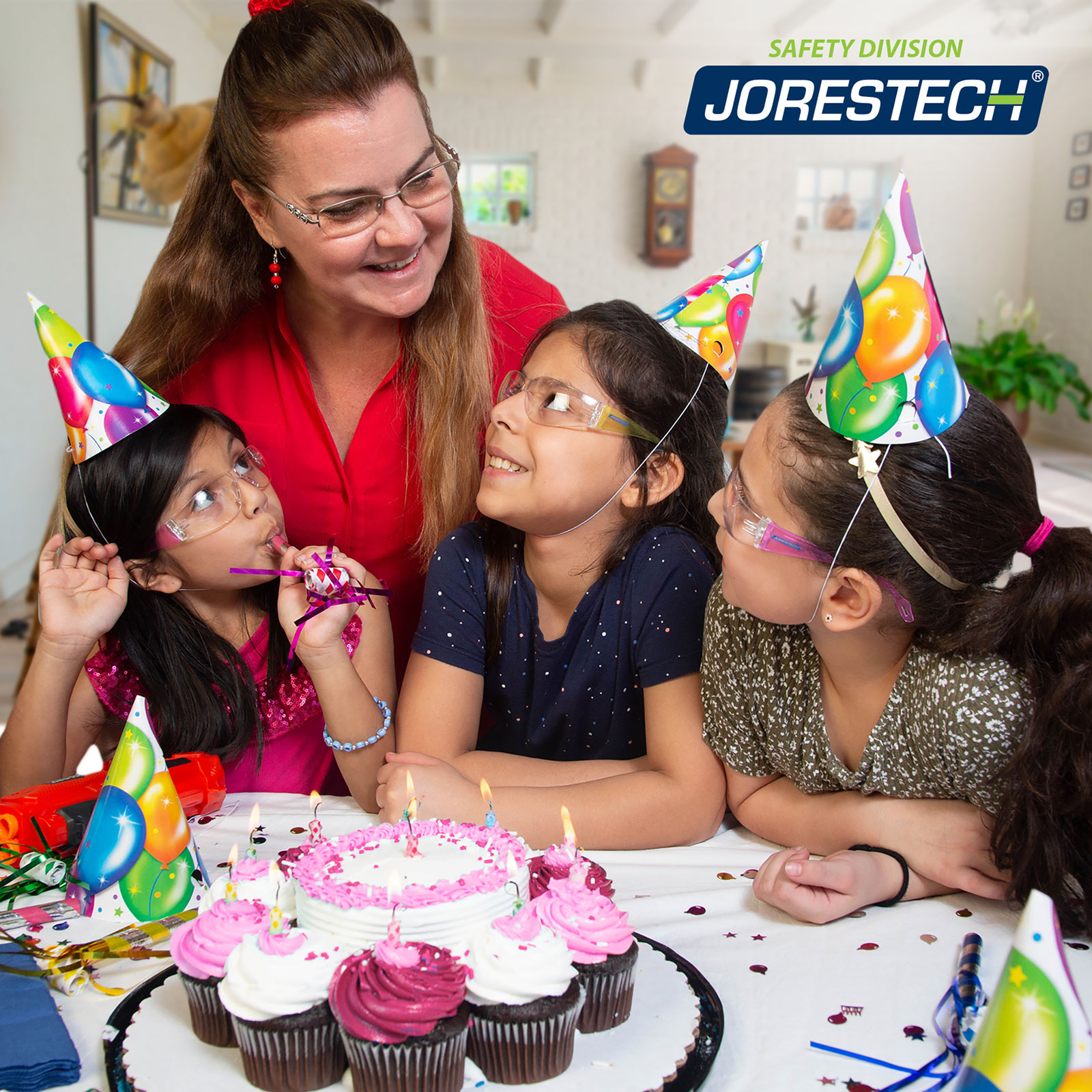 A group of 3 girls and a mother blowing candles in a birthday party.  The 3 girls are smiling while wearing JORESTECH multicolor ANSI compliant safety glasses for kids