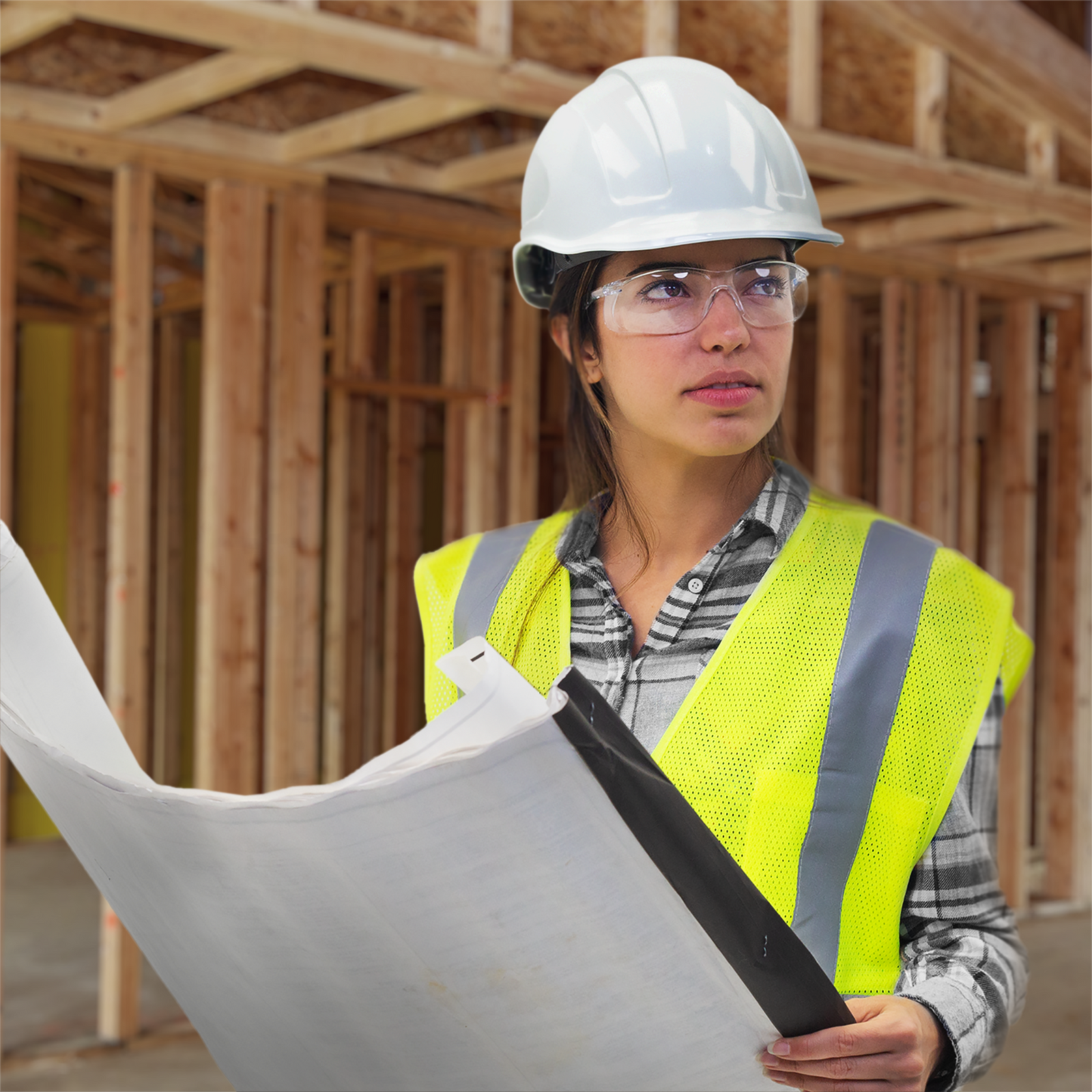 A surveyor wearing a white hard hat, a high visibility reflective safety vest and the Panoramic JORESTECH safety glasses for high impact eye protection. The person is looking at a set of blue prints related to the construction she is inspecting.