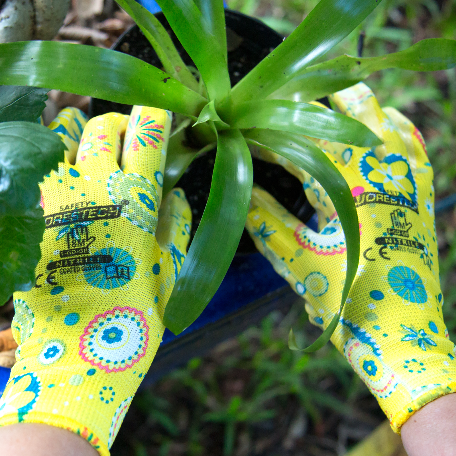 Hands wearing the JORESTECH gardening gloves with nitrile dipped palms. The person is removing a bromeliad plant from a flower pot  JORESTECH garden gloves on top