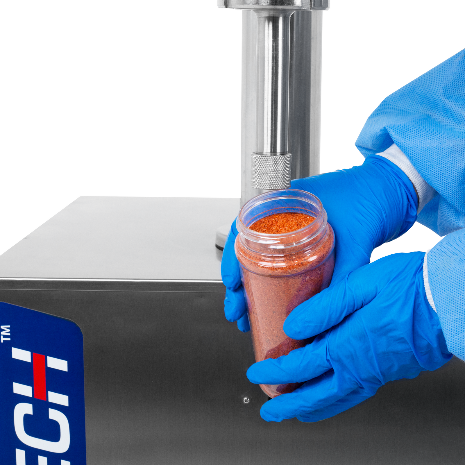 Close-up of the hands of a person with blue latex gloves and PPE holding a clear container filled with a red seasoning powder. The container is held under the dispensing nozzle of an auger powder filler, which was used to dispense seasoning powder into the container. 
