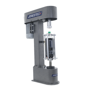 The bottle capper with JORES TECHNOLOGIES® logo on side. The machine has a plastic bottle filled with dark liquid and has a plastic green cap closing the bottle.