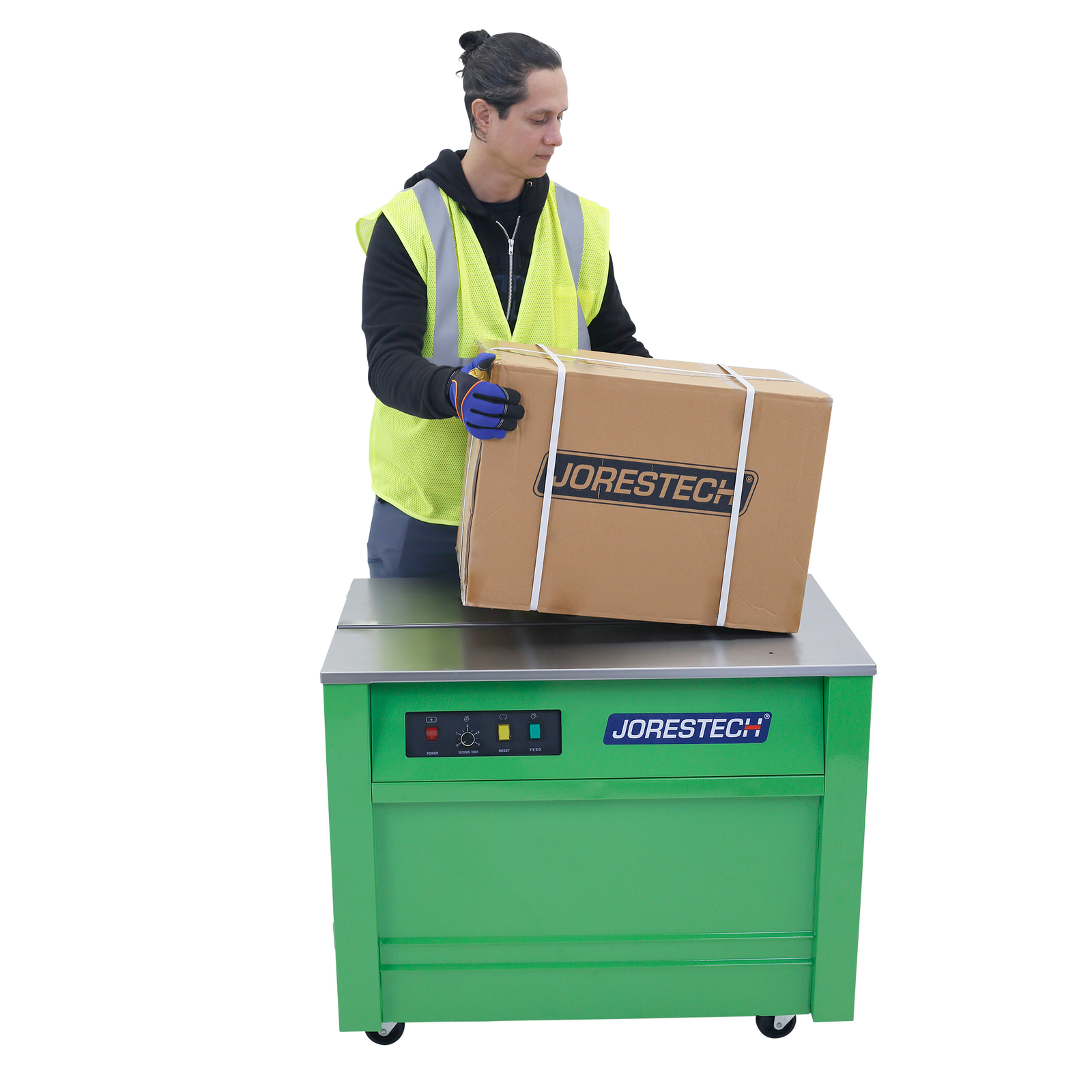 Worker operating a green Joresteck semi automatic poly strapping machine with wheels. He has a carton box positioned on top of the machine with 3 poly straps securing the box around