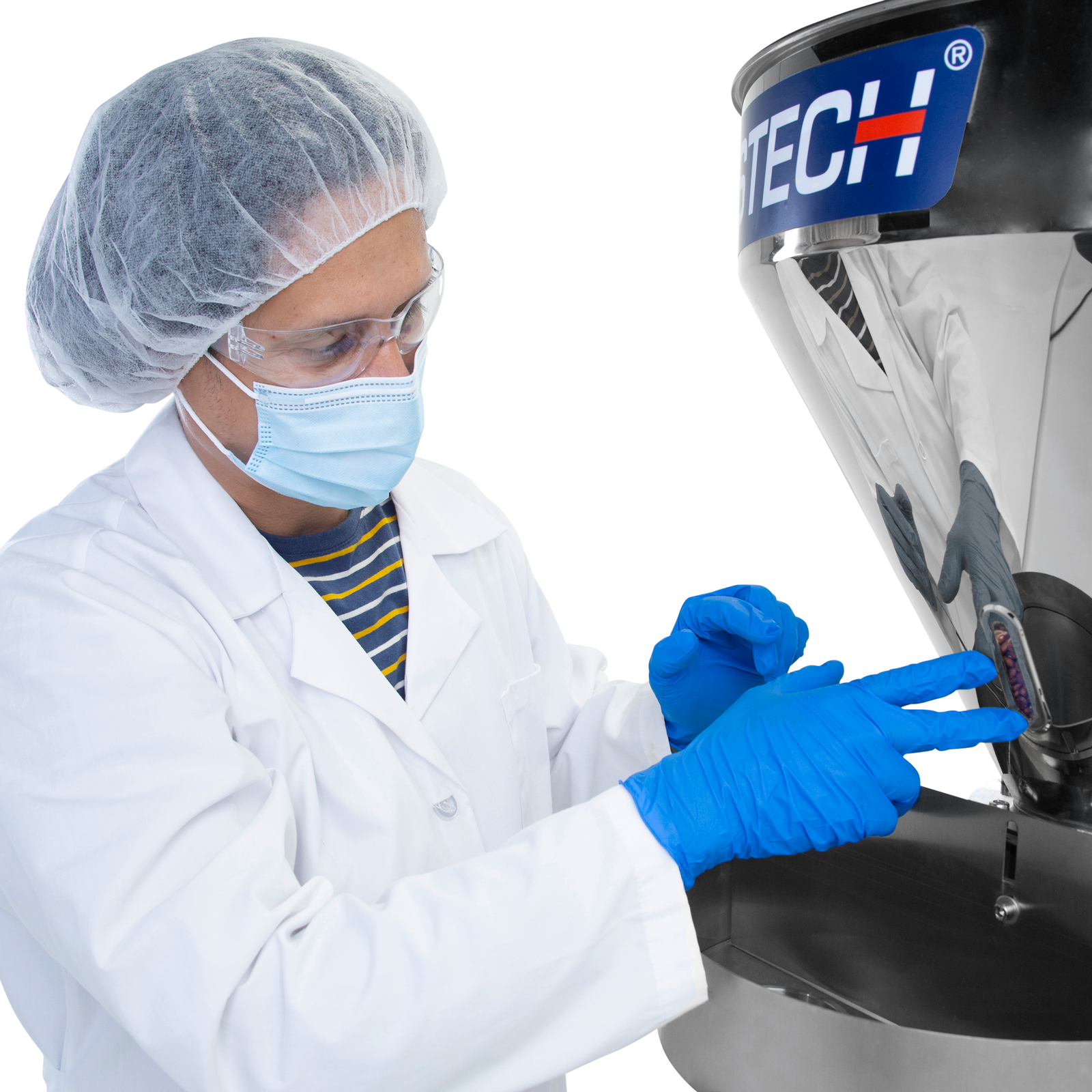A man wearing personal protection equipment next to the semi automatic volumetric filler. He is checking the level of product remaining in the hopper through the inspection window