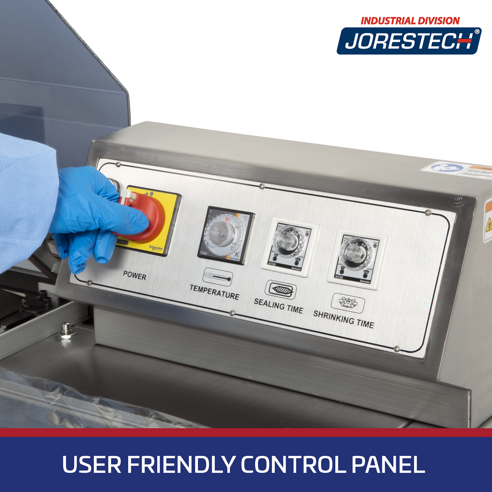 Close-up detail shot of the Stainless Steal control panel on a JORES TECHNOLOGIES® Chamber style Shrink Wrapping Machine. A hand wearing a blue glove is turning the ON / OFF switch. Control panel shows temperature control, sealing time and shrinking time twist knobs. Blue banner on the bottom with white letters says User Friendly Control Panel.
