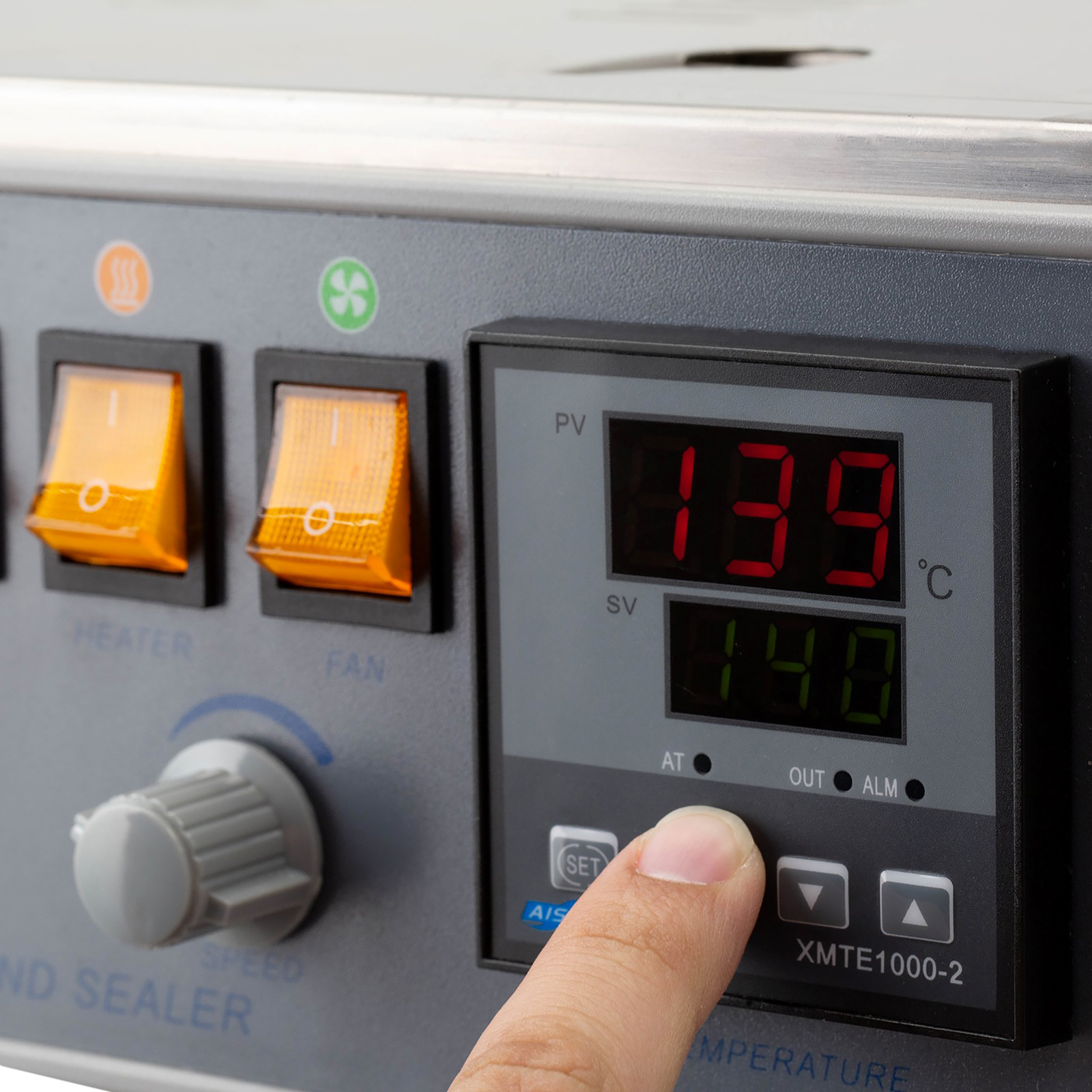 the hand of an operator setting the heating temperature on the digital panel of the JORESTECH continuous band sealer