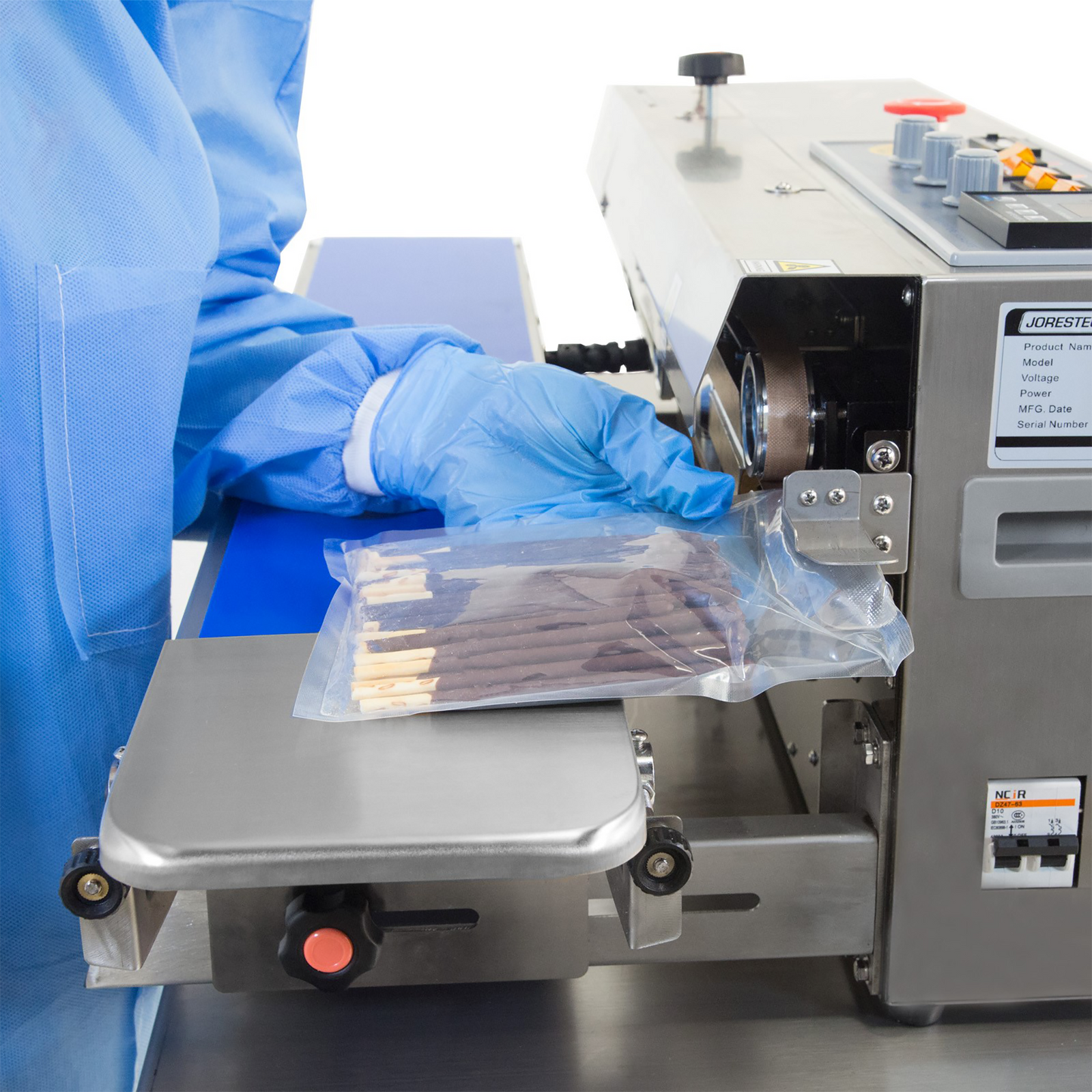 operator inserting plastic bags filled with chocolate sticks into the JORES TECHNOLOGIES® continuous band sealer to seal the bags. Bag sealer is set for horizontal applications.