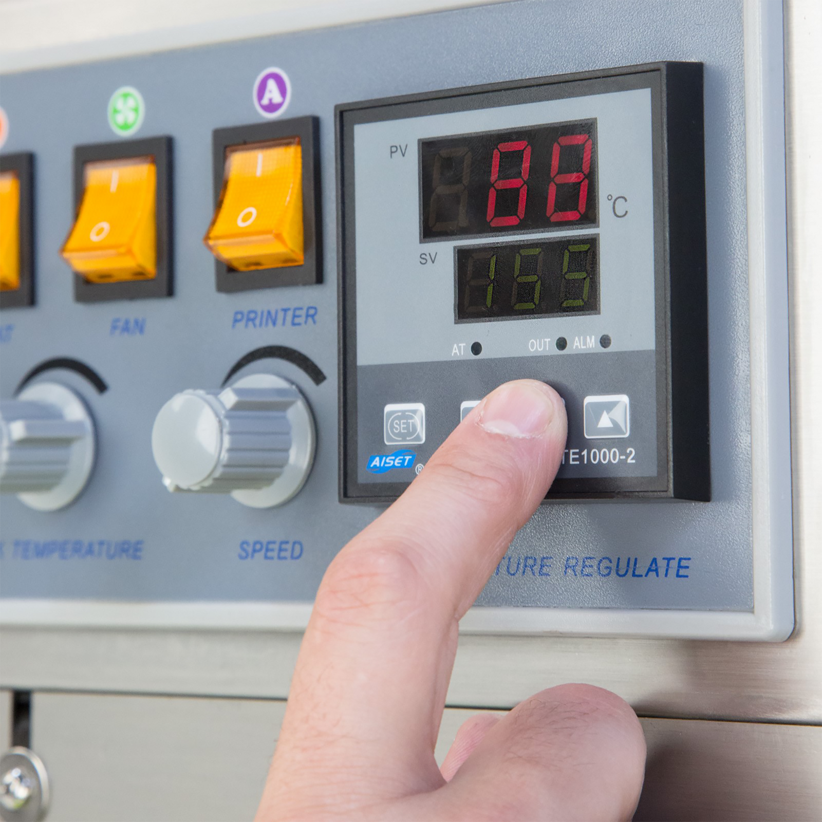 operator adjusting the heating temperature on the digital temperature regulator of the JORES TECHNOLOGIES® digital continuous bag sealer