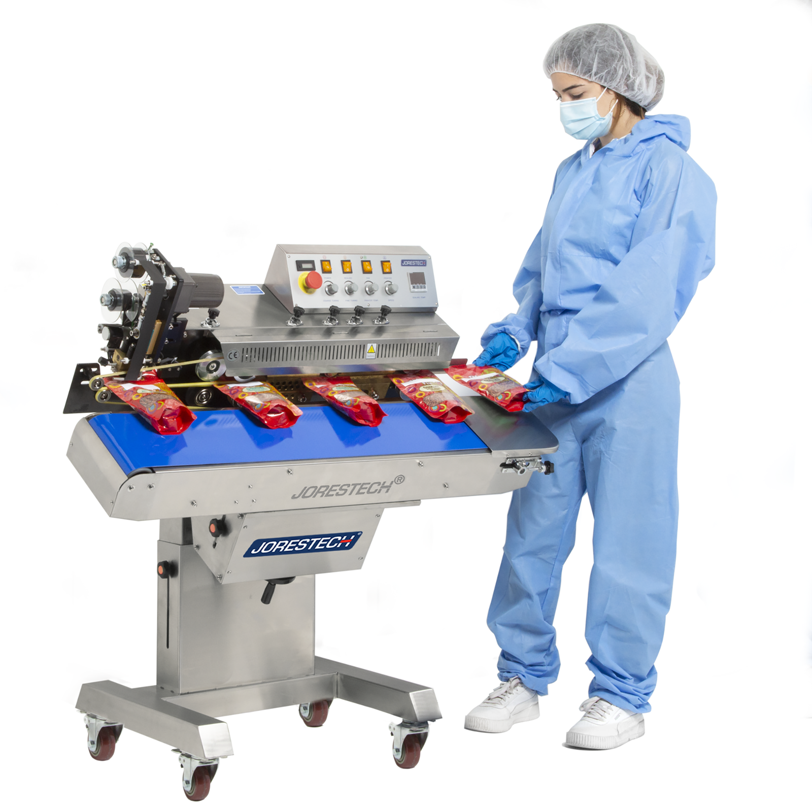 operator wearing blue overall inserting red plastic bag to be sealed and codded by stainless steel JORESTECH continuous band sealer. All the machine except the base is tilted forward showing that the machine can be adjusted to horizontal or to a tilted position