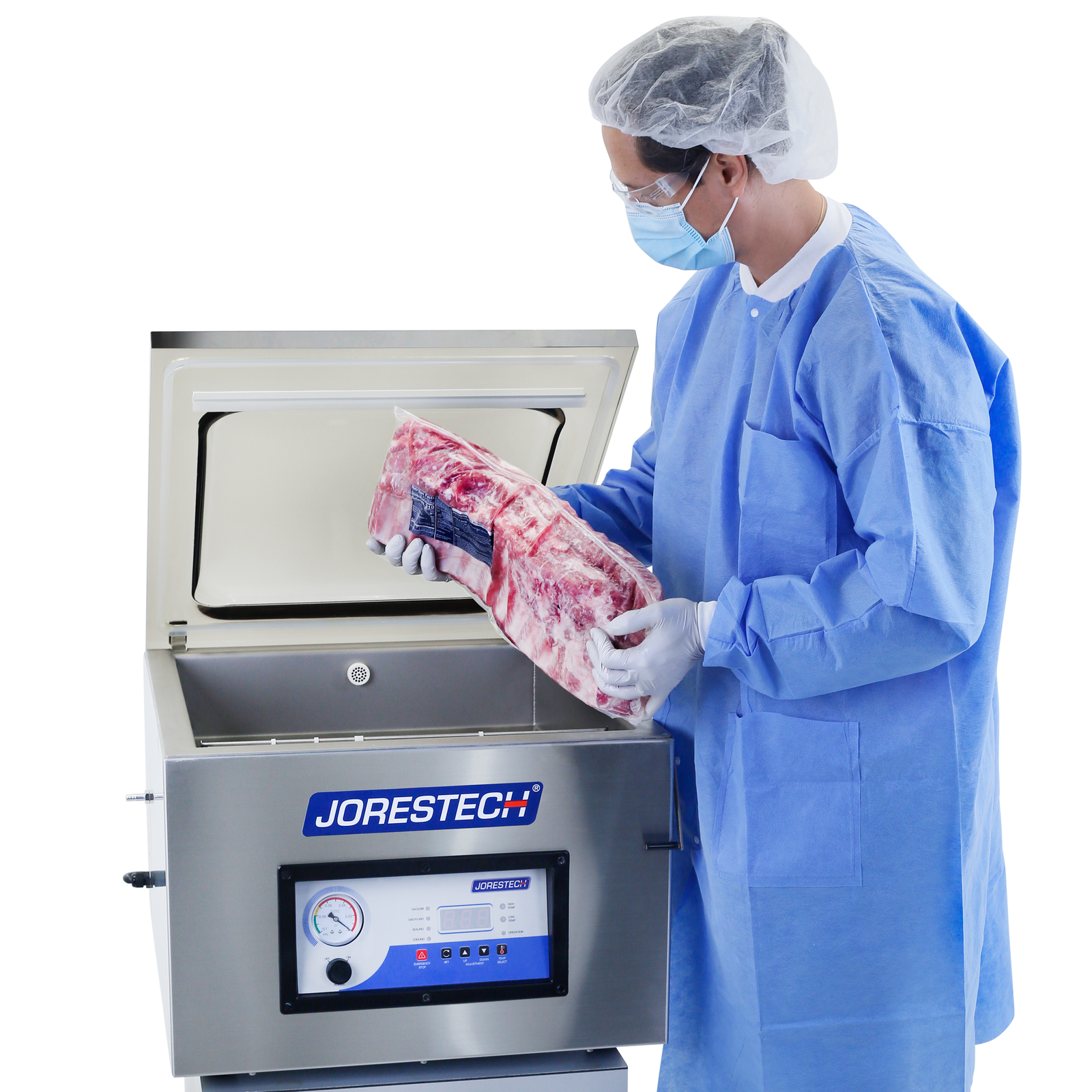 Operator wearing a blue PPE gown, a face mask, latex gloves and a hair net holding a package with freshly sealed red meat. He is removing the vacuumed meat from the inside of the stainless steel table top single chamber vacuum sealer